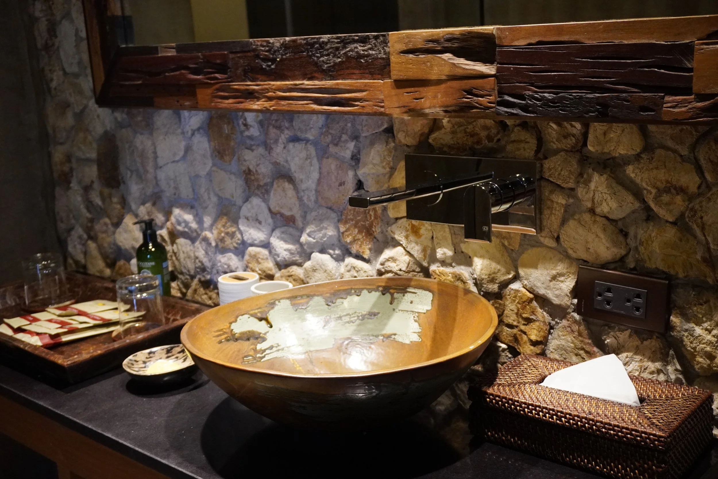 Natural stone bathroom with handcrafted wooden basin and premium amenities