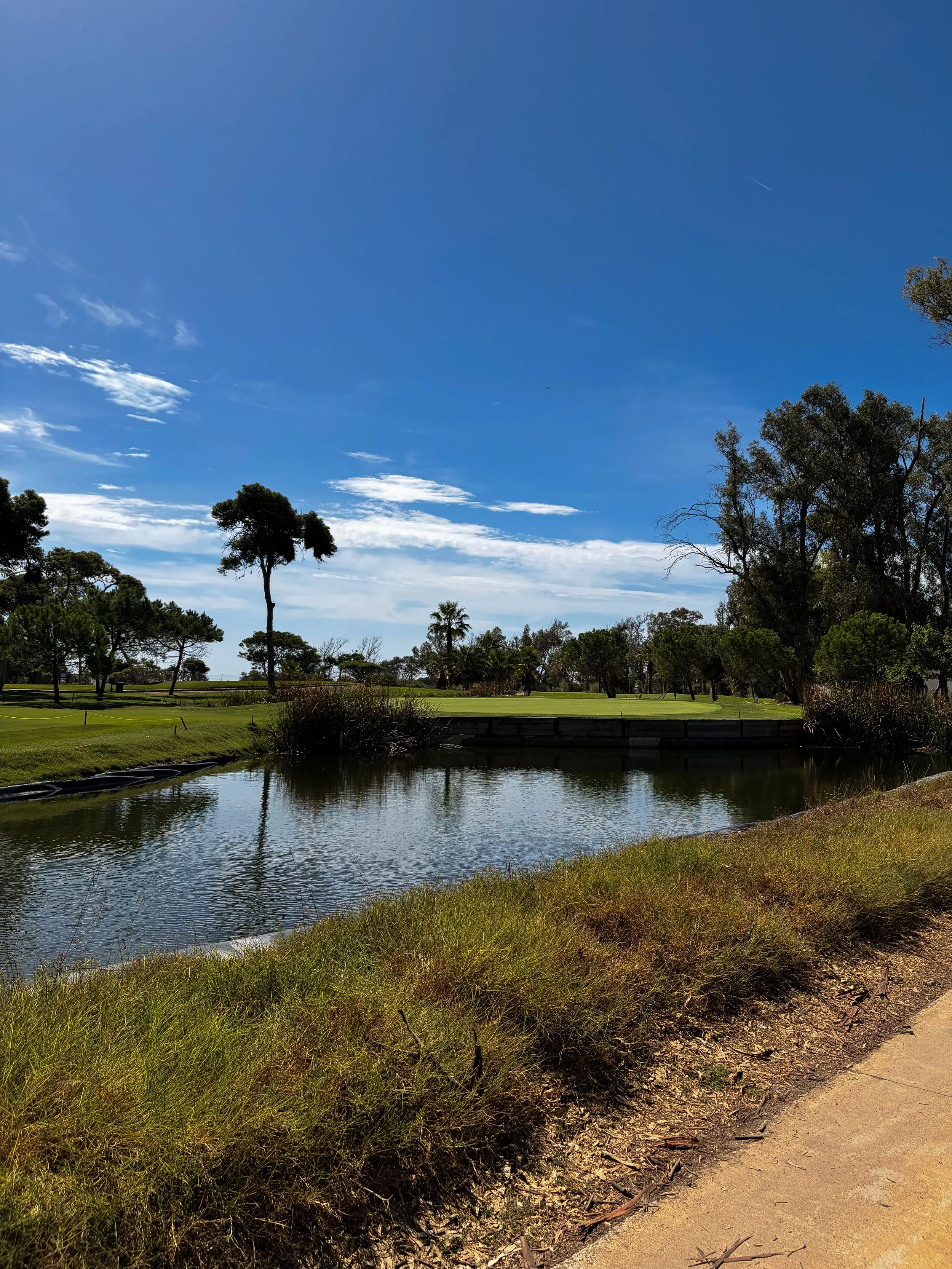 Landscaped golf course with peaceful water features beneath a clear blue sky