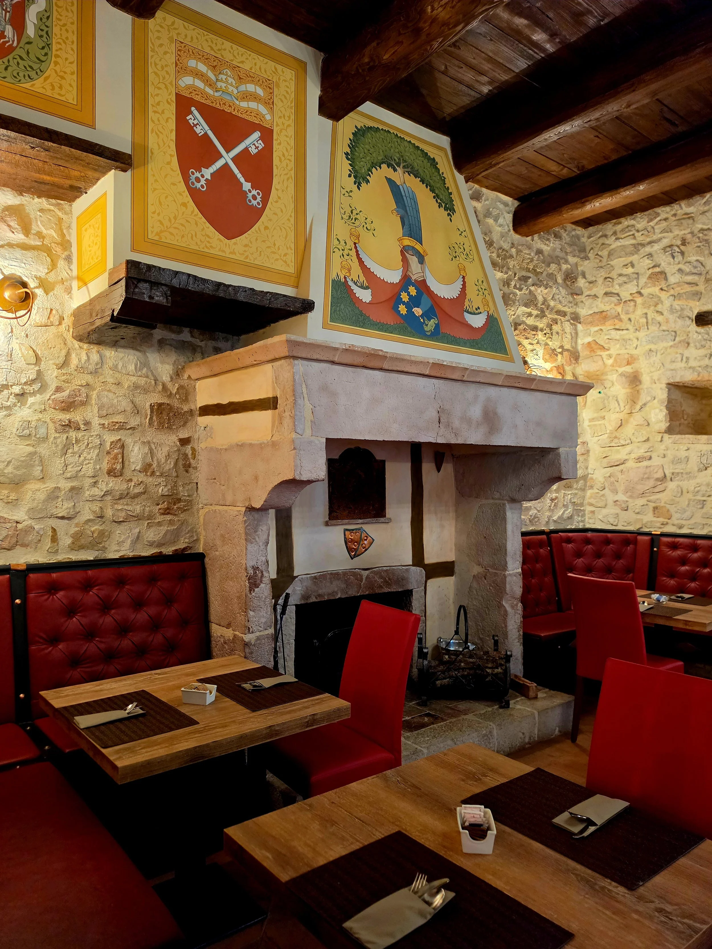 Rustic restaurant featuring a historic fireplace, stone walls, and elegant dining spaces