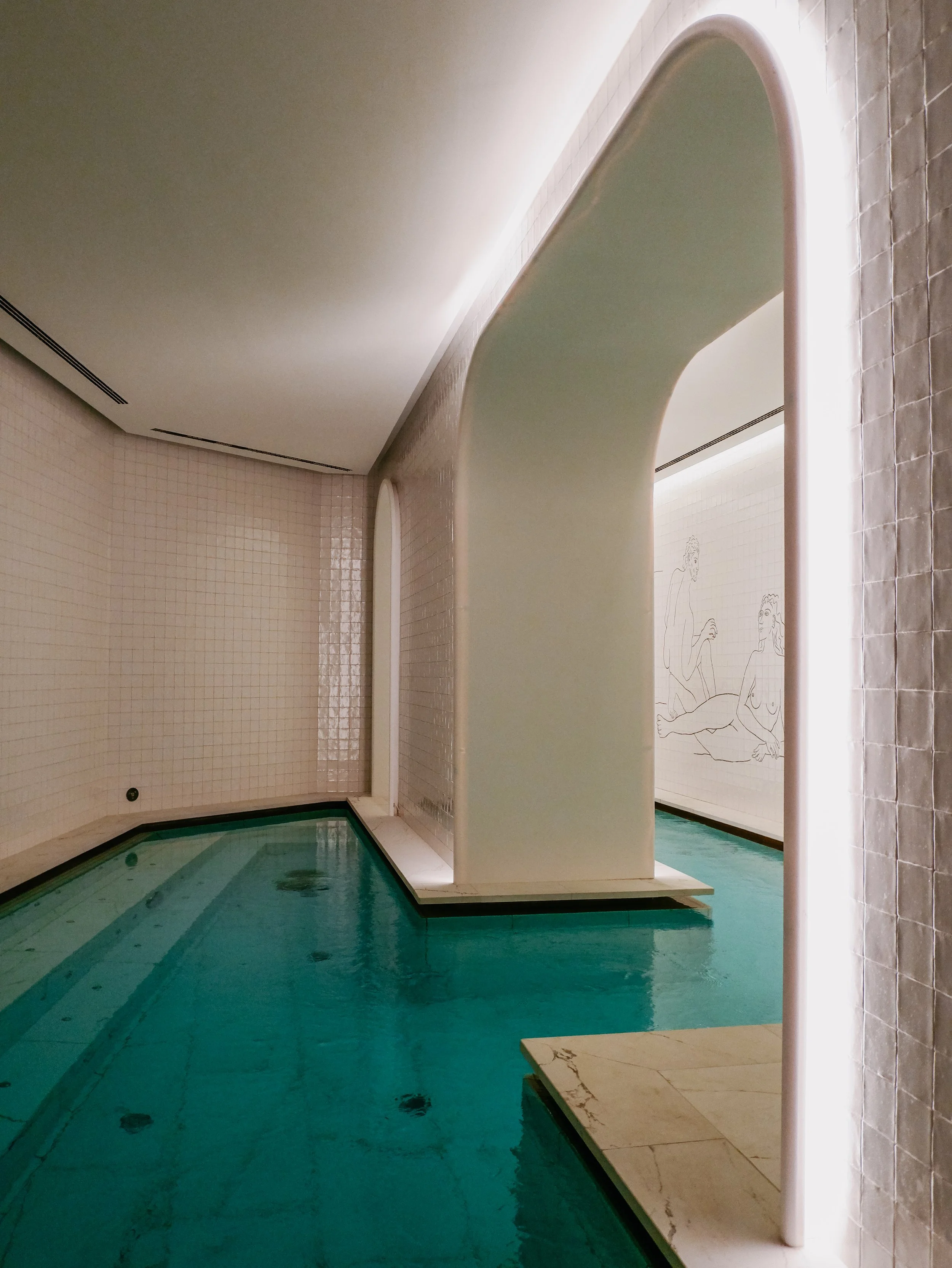 Indoor wellness pool beneath elegant illuminated arches and tiled walls