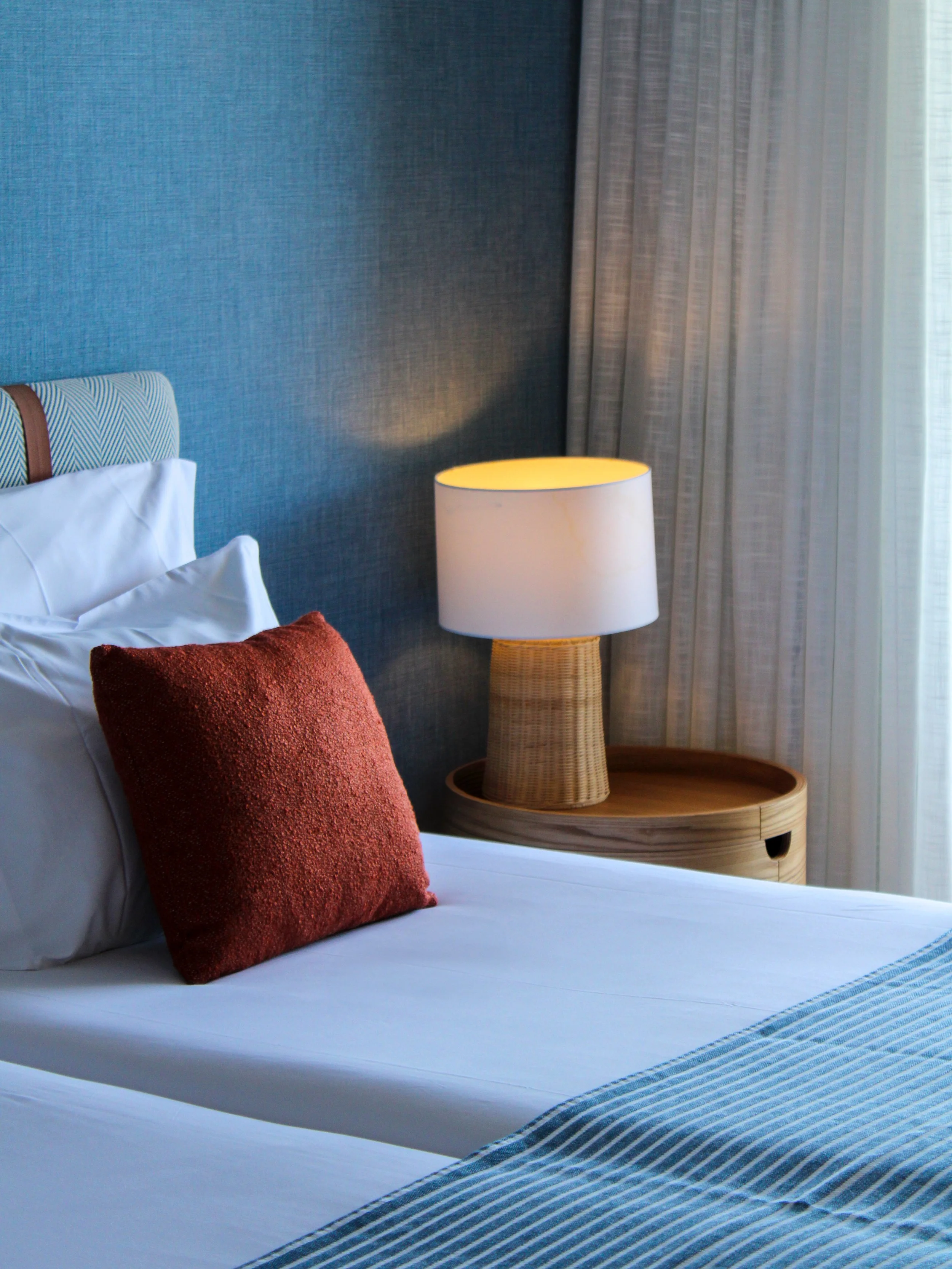 Contemporary guest room with plush bedding, warm lighting, and calming coastal-inspired design