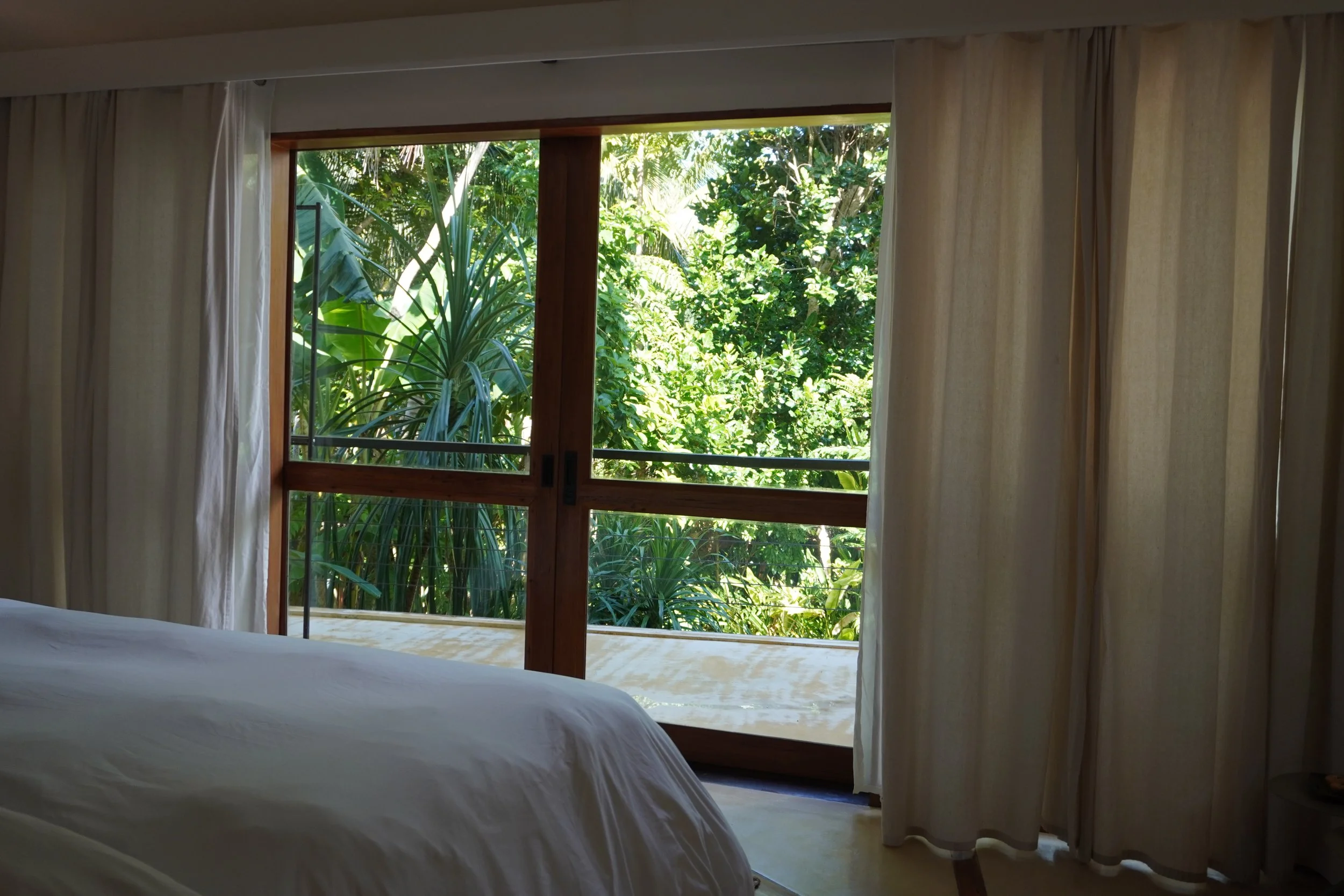 Peaceful bedroom opening onto a private terrace surrounded by lush tropical gardens