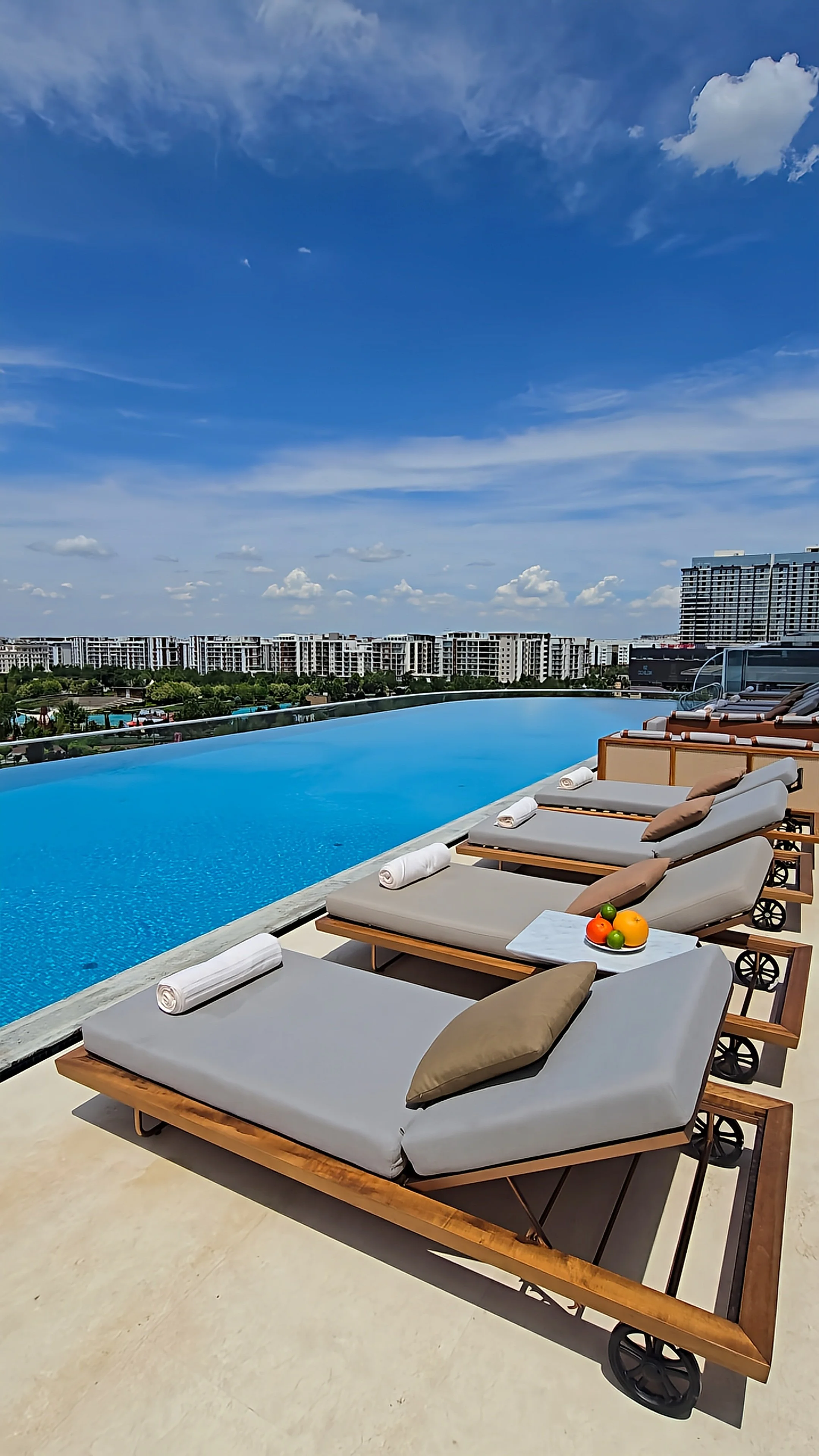 Rooftop infinity pool with luxury sun loungers overlooking the skyline of Tashkent at JW Marriott Hotel Tashkent