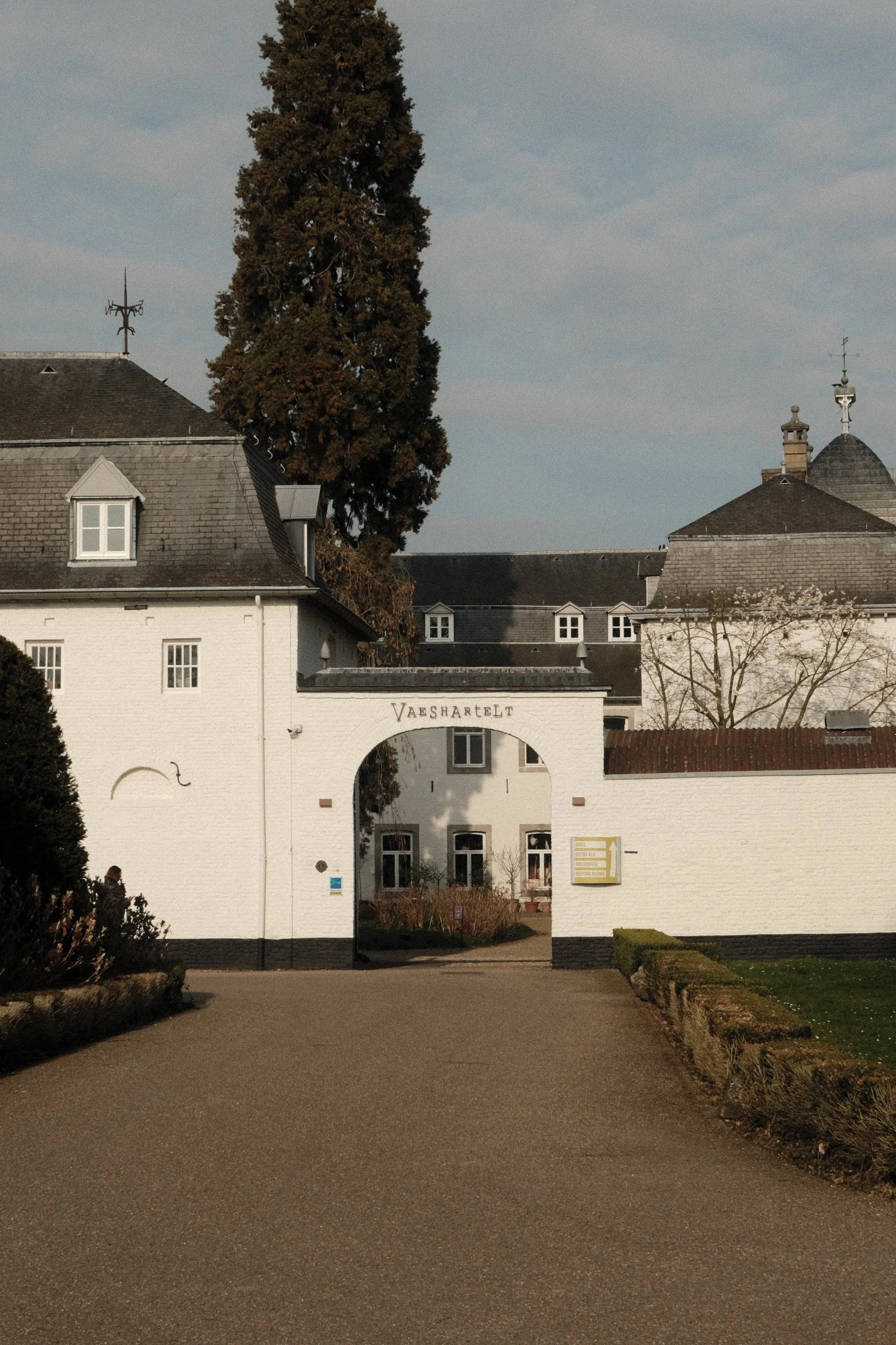 Grand entrance gate framed by historic architecture and landscaped grounds in soft afternoon light, Château St. Gerlach – Vaeshartelt Maastricht.