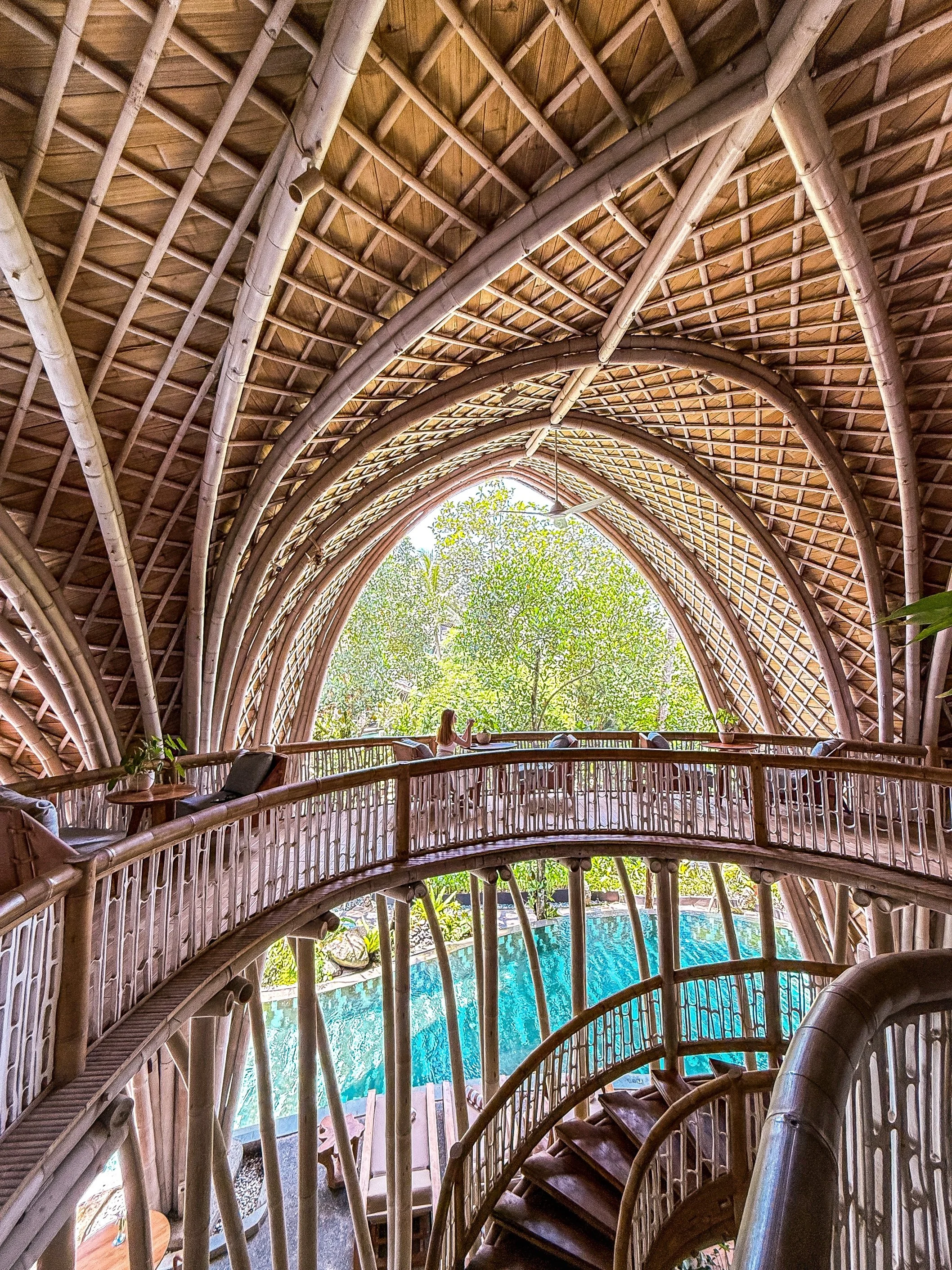 Interior of bamboo architecture with curved design overlooking pool at Ulaman Eco Luxury Resort Bali