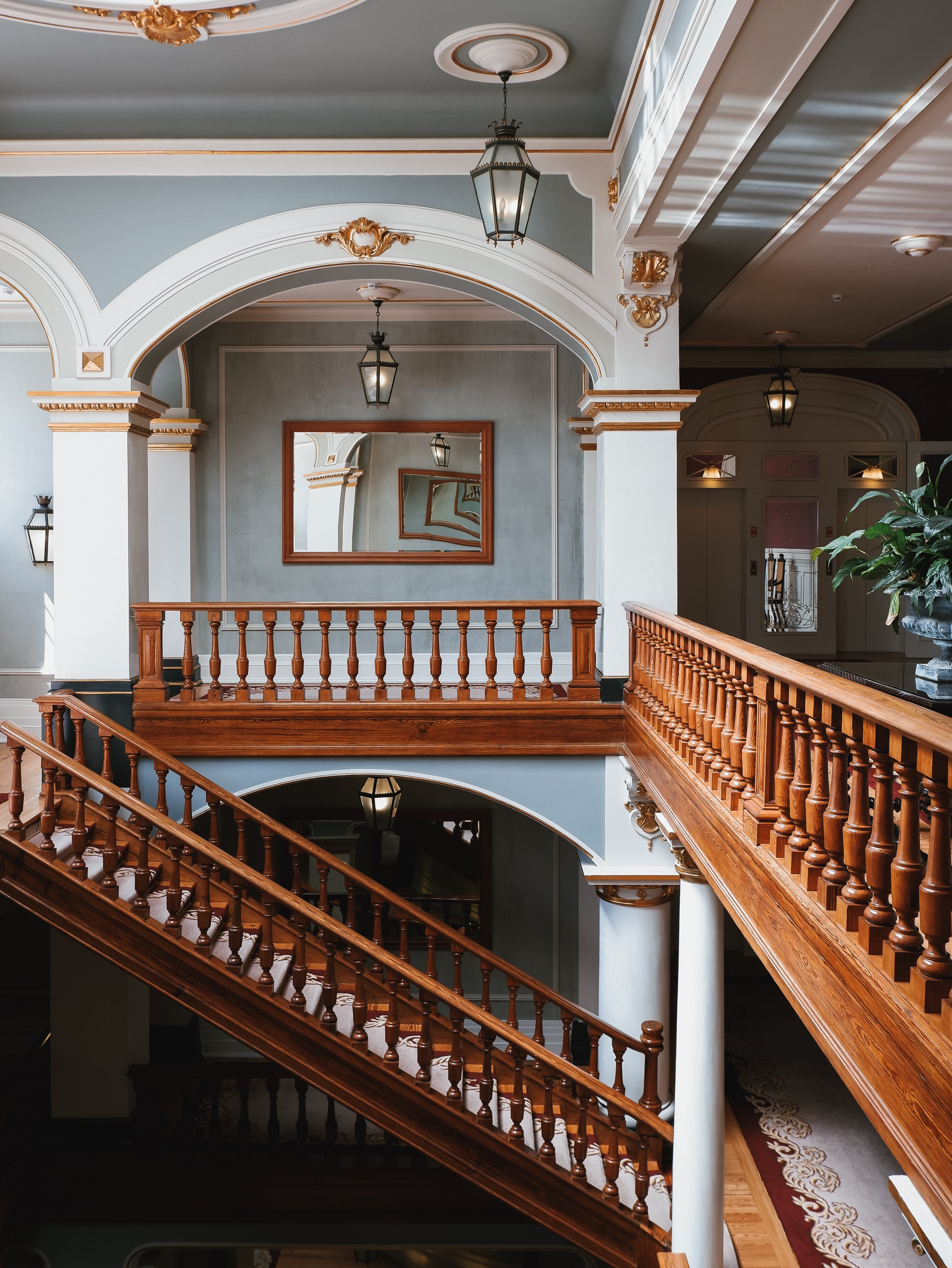 Grand heritage staircase showcasing handcrafted woodwork, elegant arches, period lighting, and timeless Belle Époque architecture.