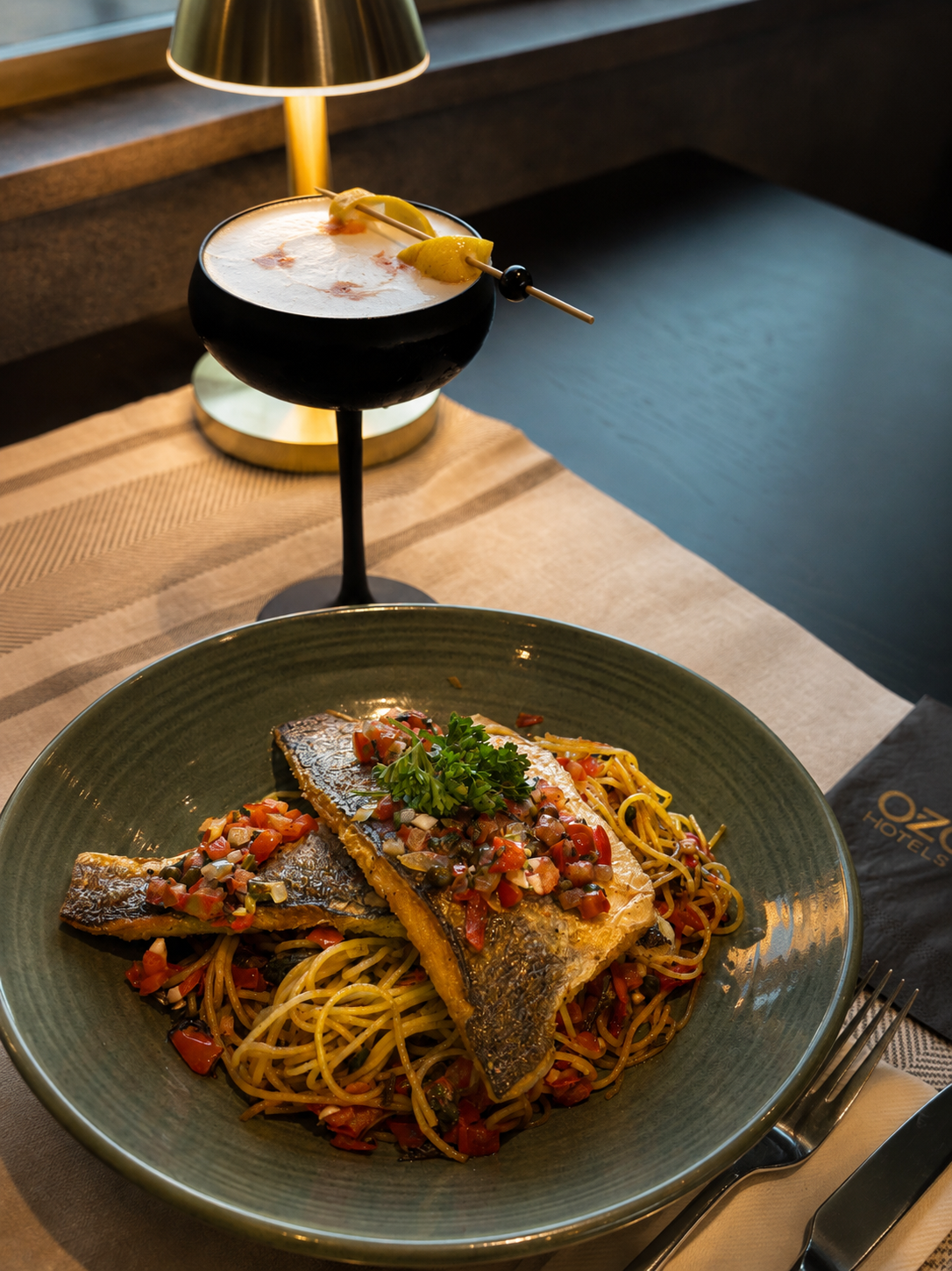 Mediterranean-style sea bass served with pasta and handcrafted cocktail