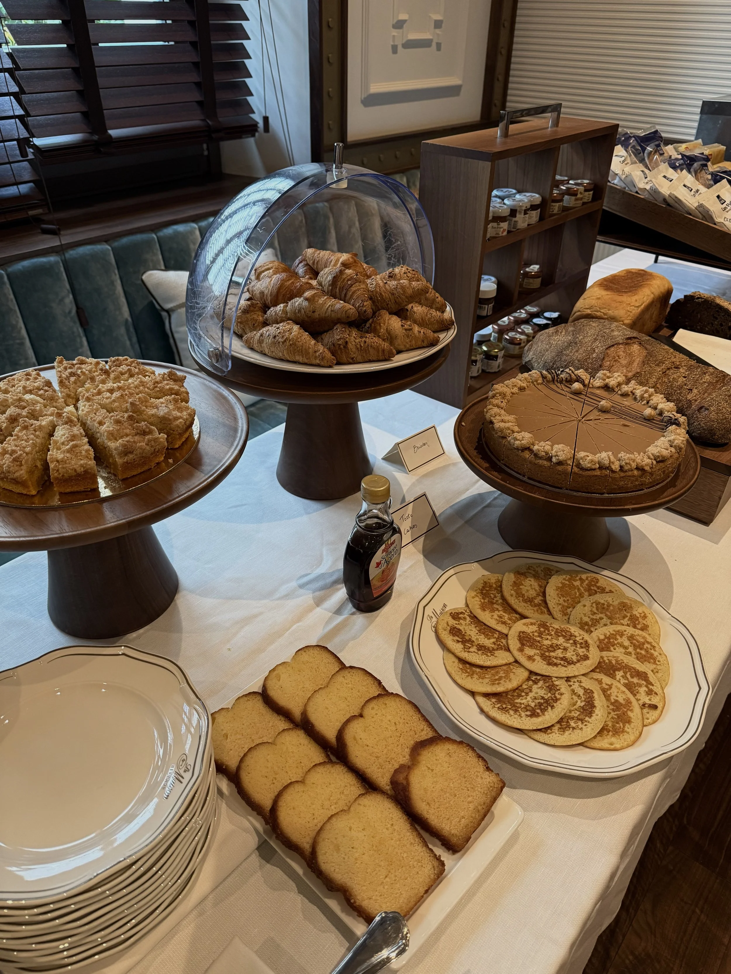 Breakfast buffet with croissants, cakes, pancakes, bread, and other freshly prepared pastries