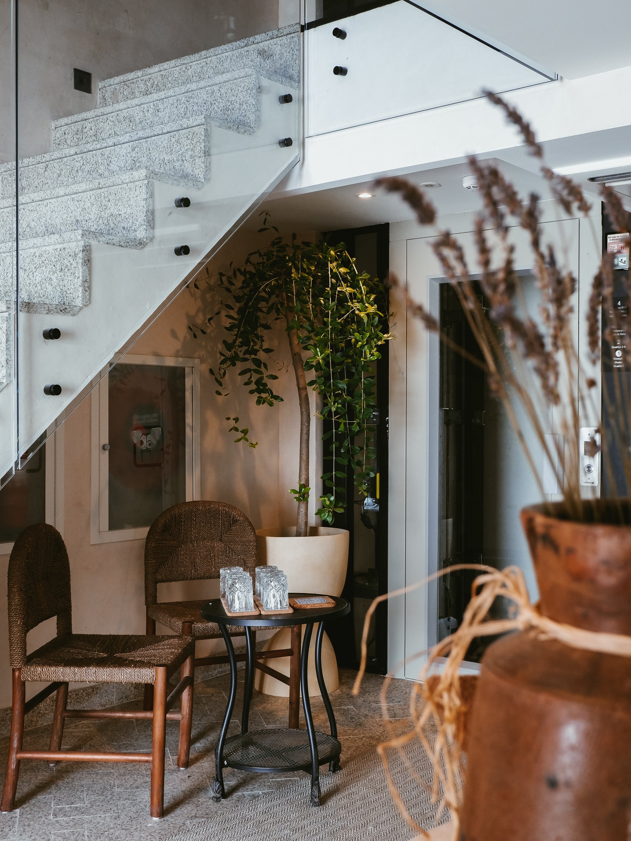 Intimate hotel interior with natural greenery, rustic seating, stone details, and contemporary design