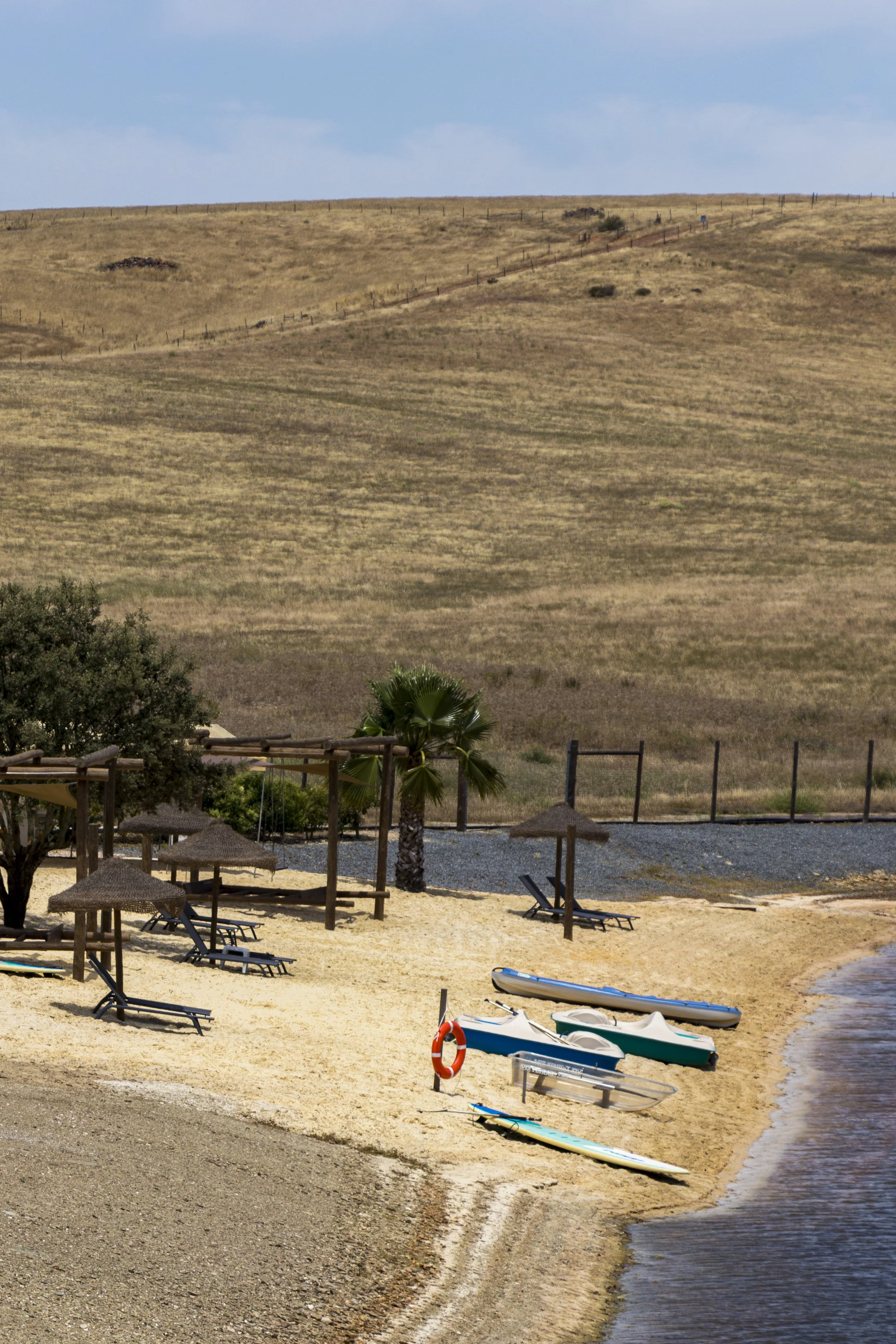 Private lakeside beach with kayaks, paddleboards, sun loungers, and peaceful Alentejo scenery
