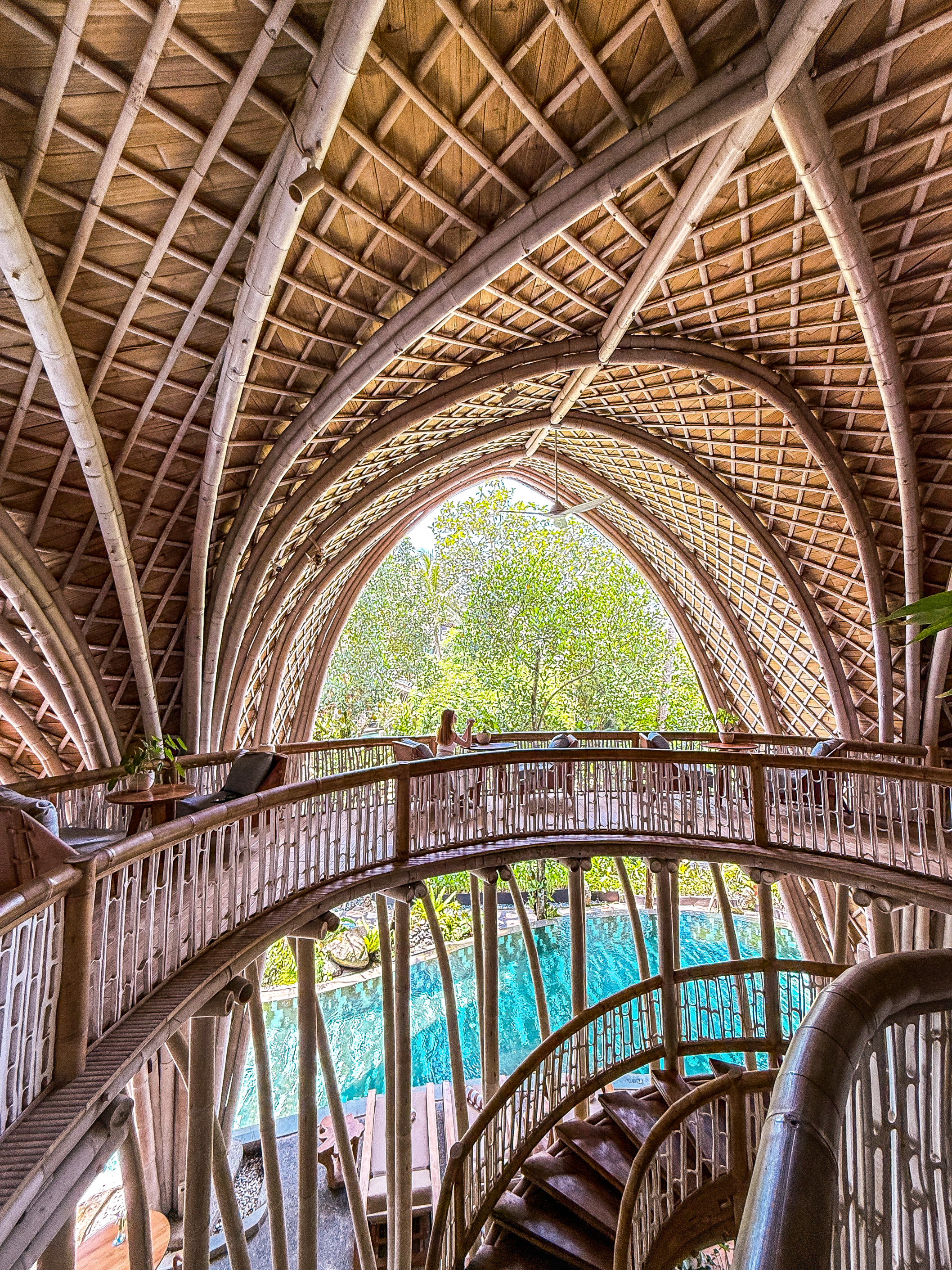 The sweeping bamboo interior showcases remarkable sustainable architecture with curved walkways overlooking the central swimming pool
