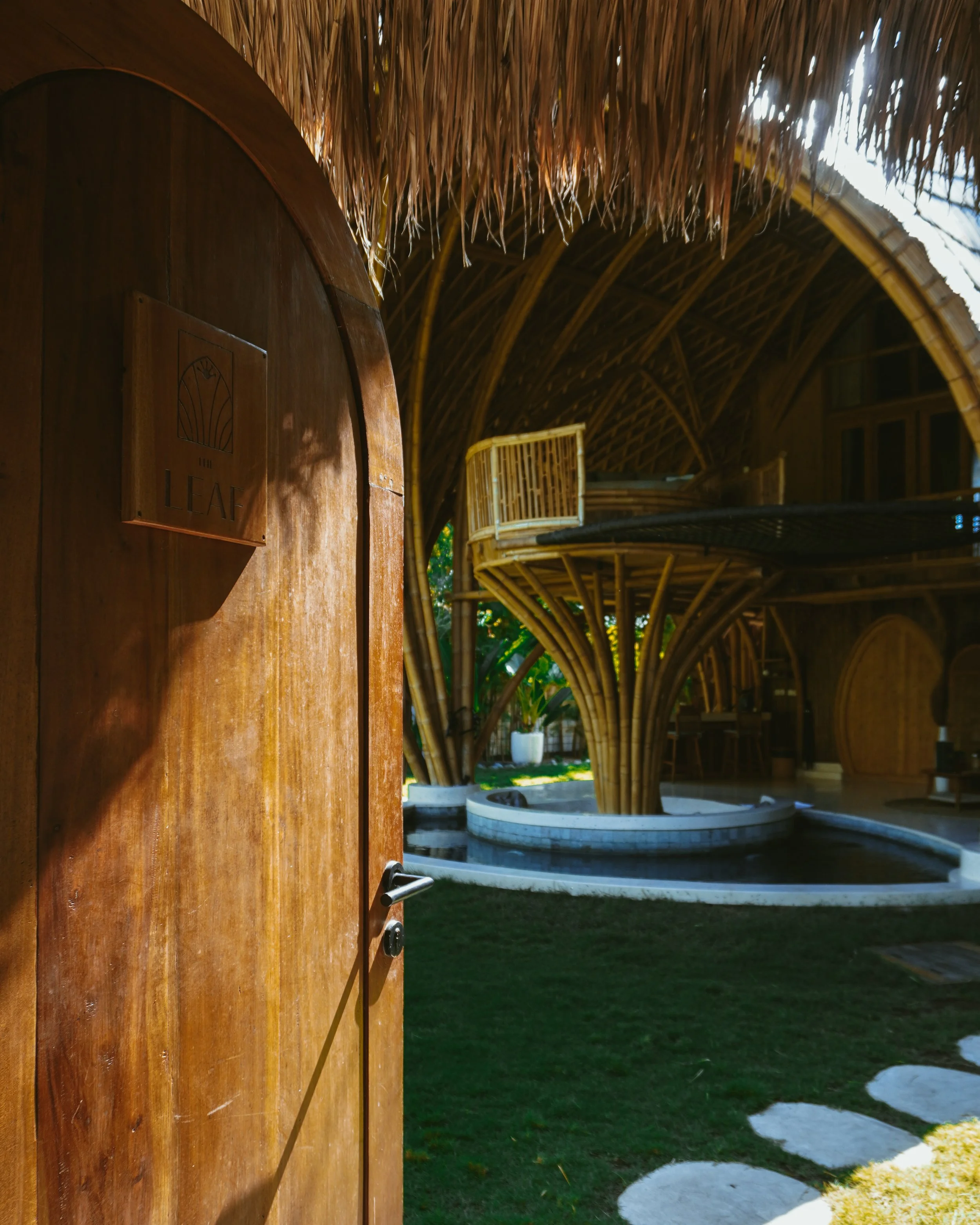 Open wooden door leading into a bamboo-designed villa with organic architecture at Villa Tokay in Gili Air