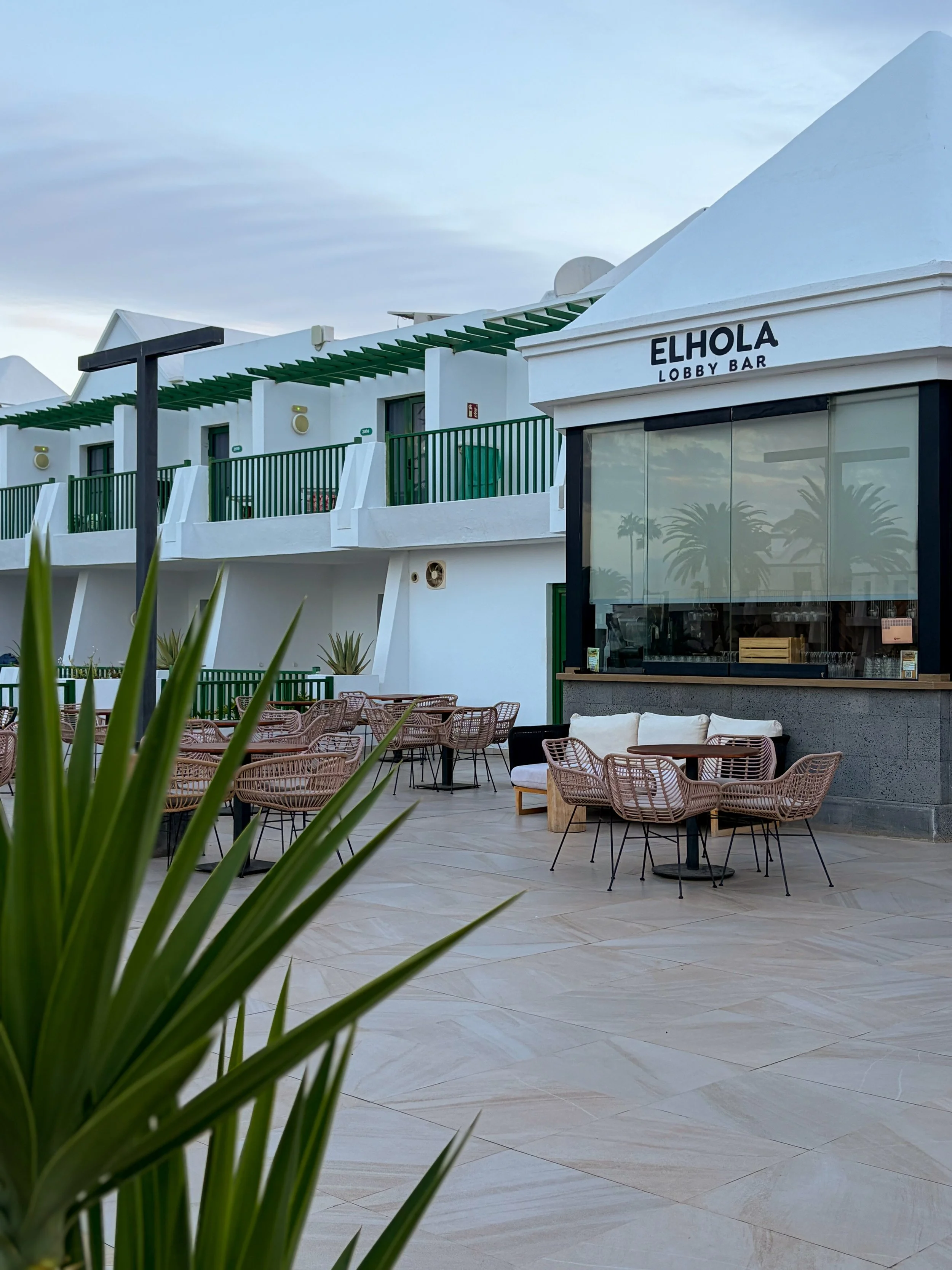 ELHOLA Lobby Bar outdoor terrace featuring wicker chairs, comfortable sofas, and whitewashed hotel architecture