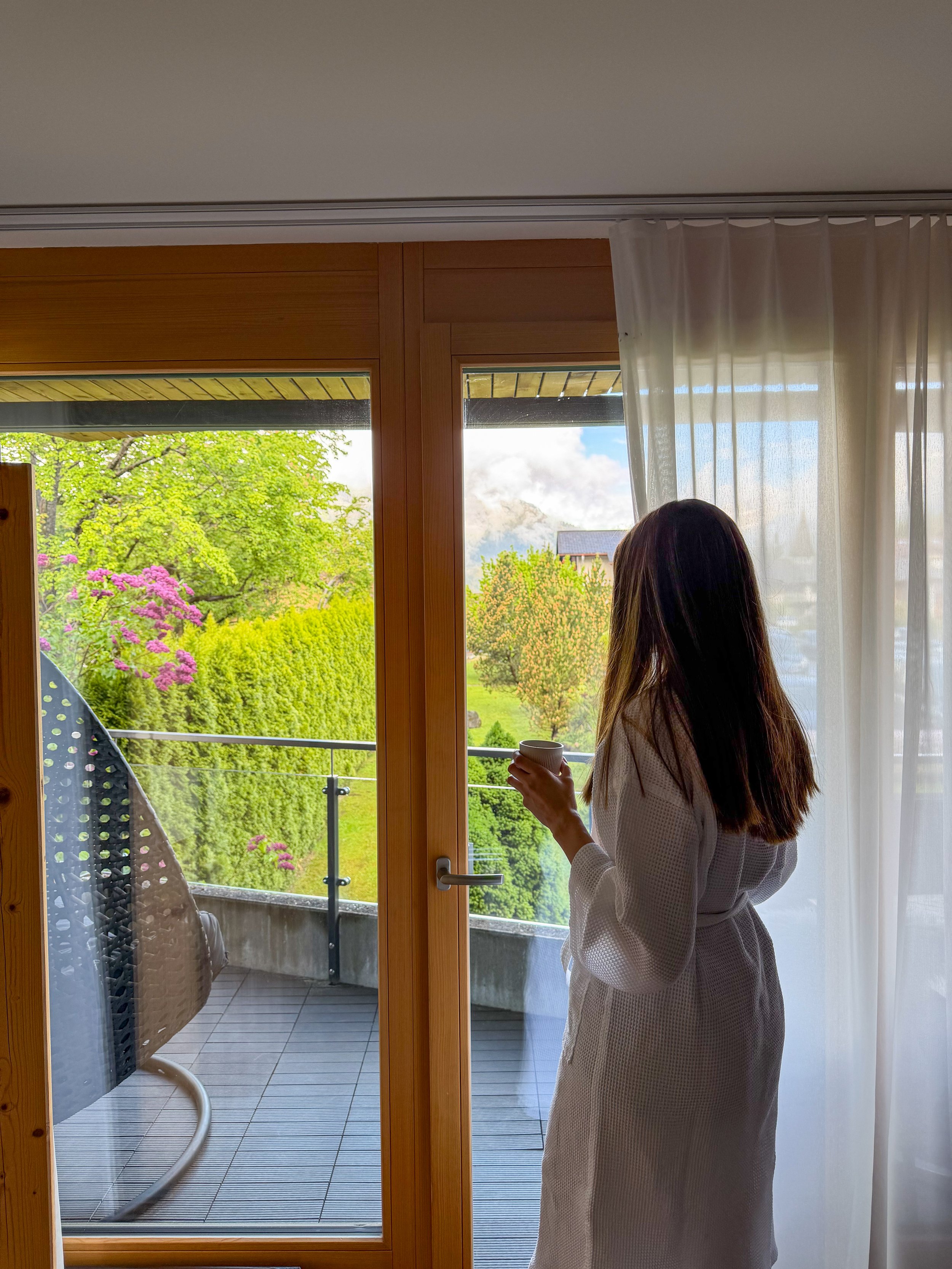 Guest enjoying a peaceful morning coffee on a private balcony surrounded by gardens and mountain scenery at Eiger Mountain & Spa Soul Resort