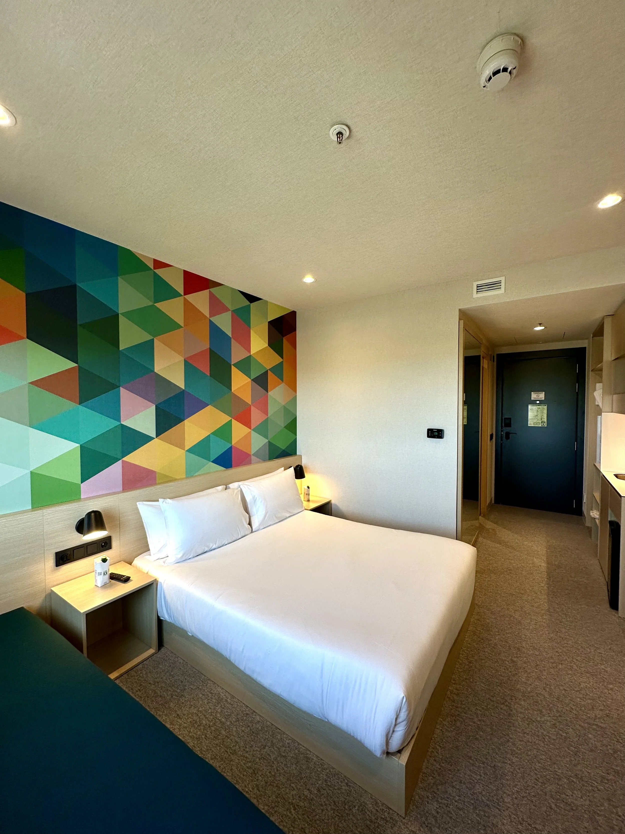 Bright guest room featuring colourful geometric artwork and minimalist interiors