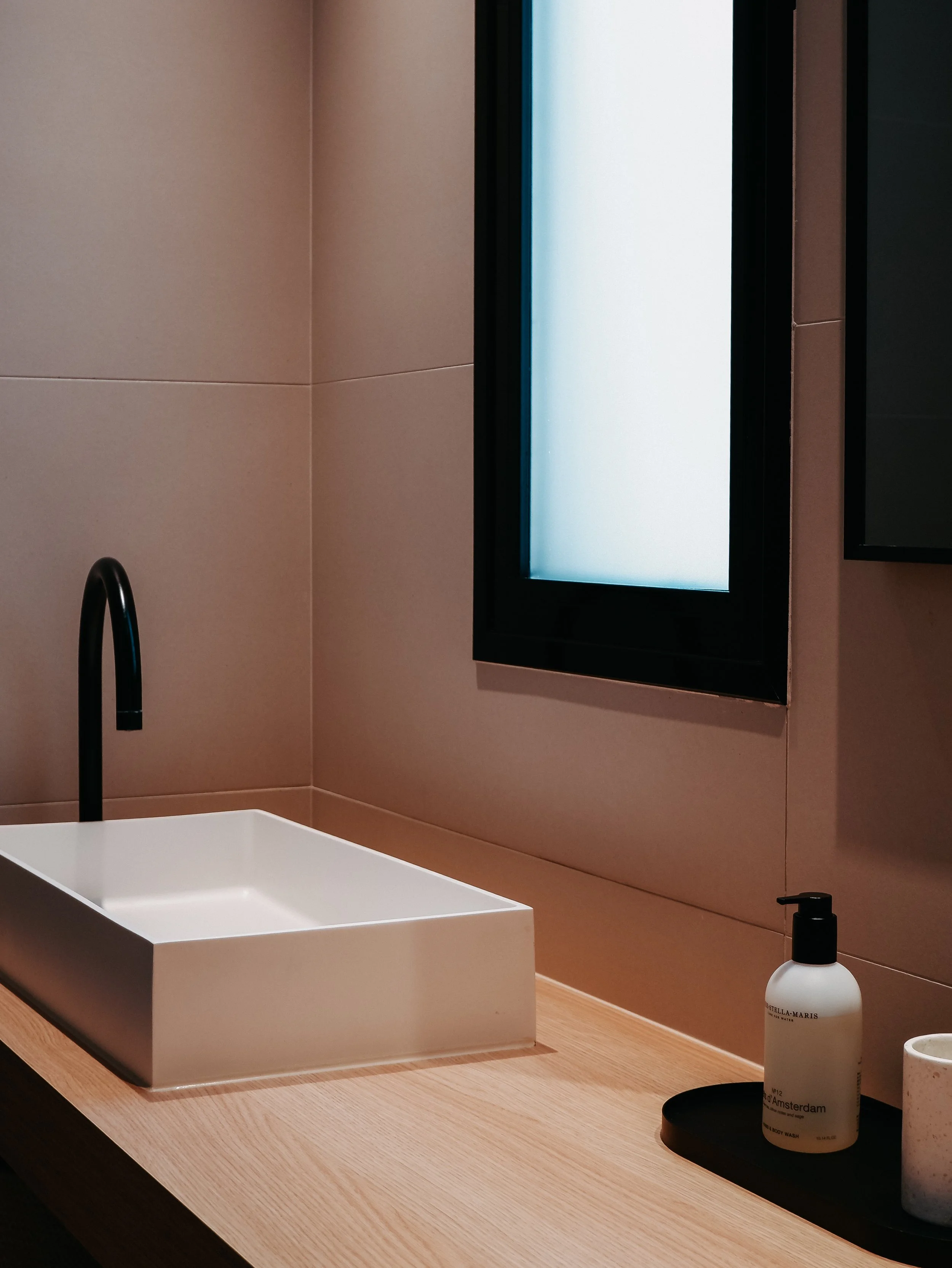 Modern bathroom featuring natural wood finishes, matte black fixtures, and premium amenities
