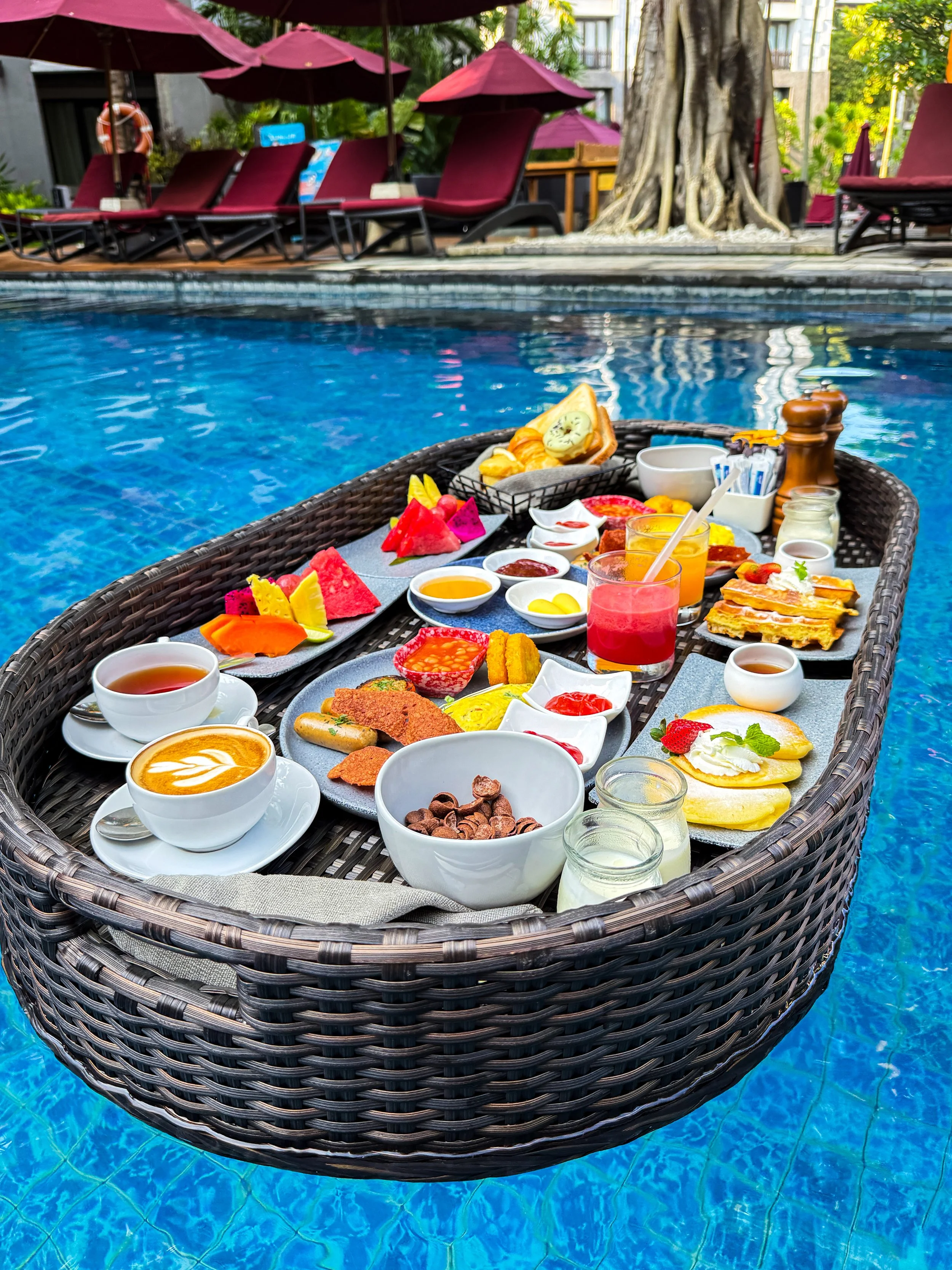 A floating breakfast showcases tropical fruit, fresh pastries, coffee, and cooked breakfast favourites served in the swimming pool