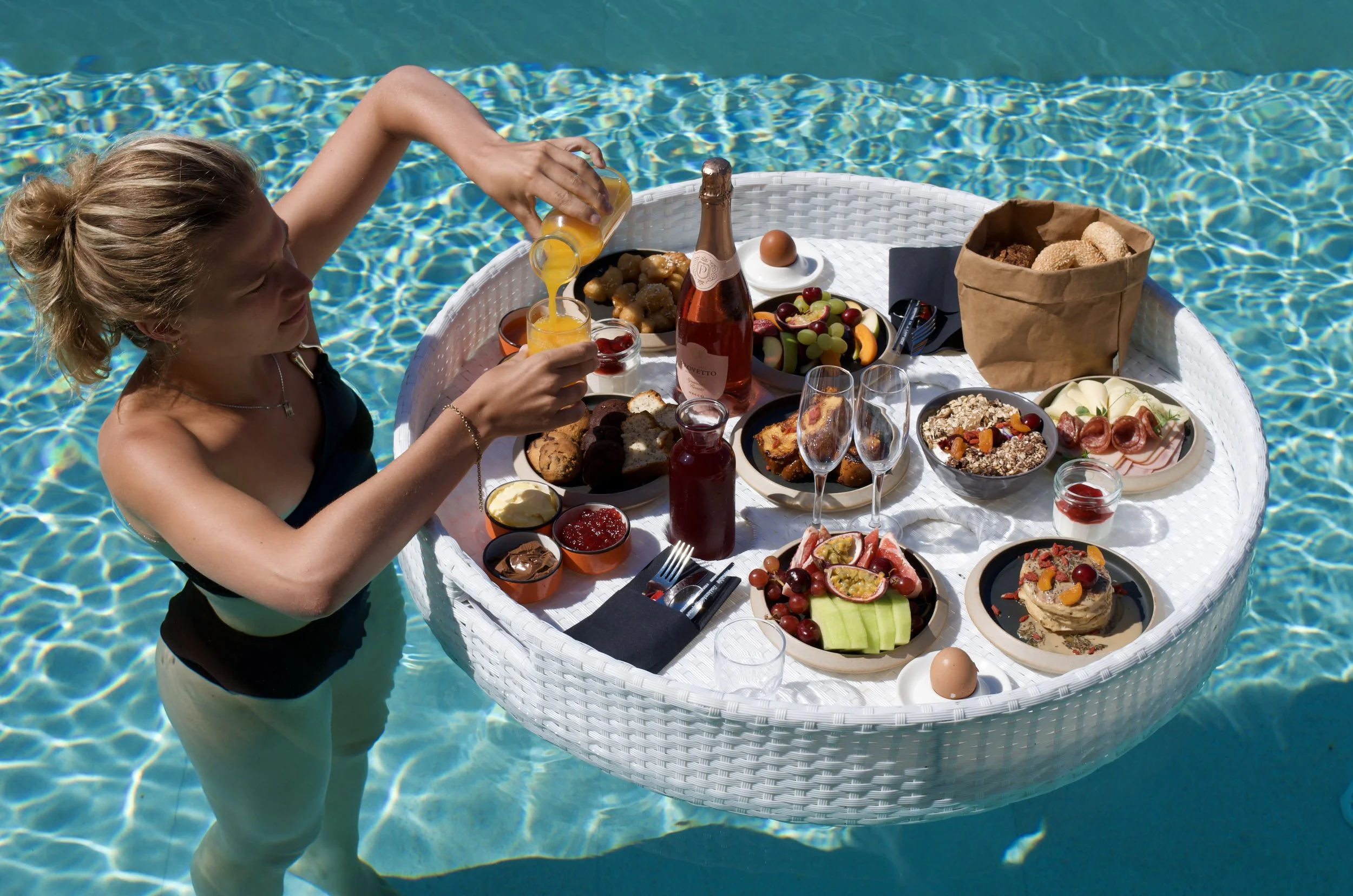 Floating breakfast served in the swimming pool with fresh fruit, pastries, sparkling wine, and morning sunshine