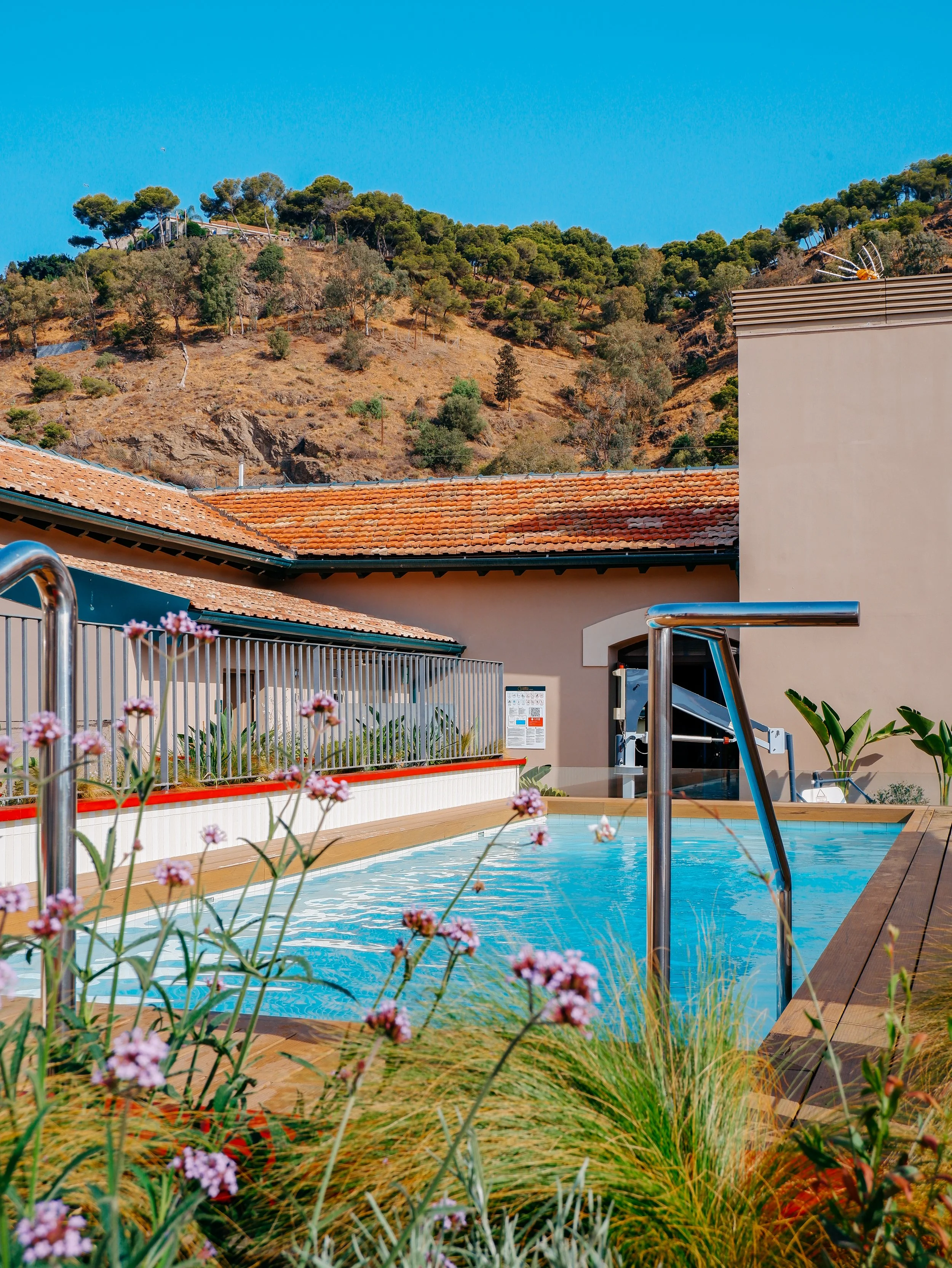 Outdoor swimming pool surrounded by landscaped gardens and hillside views