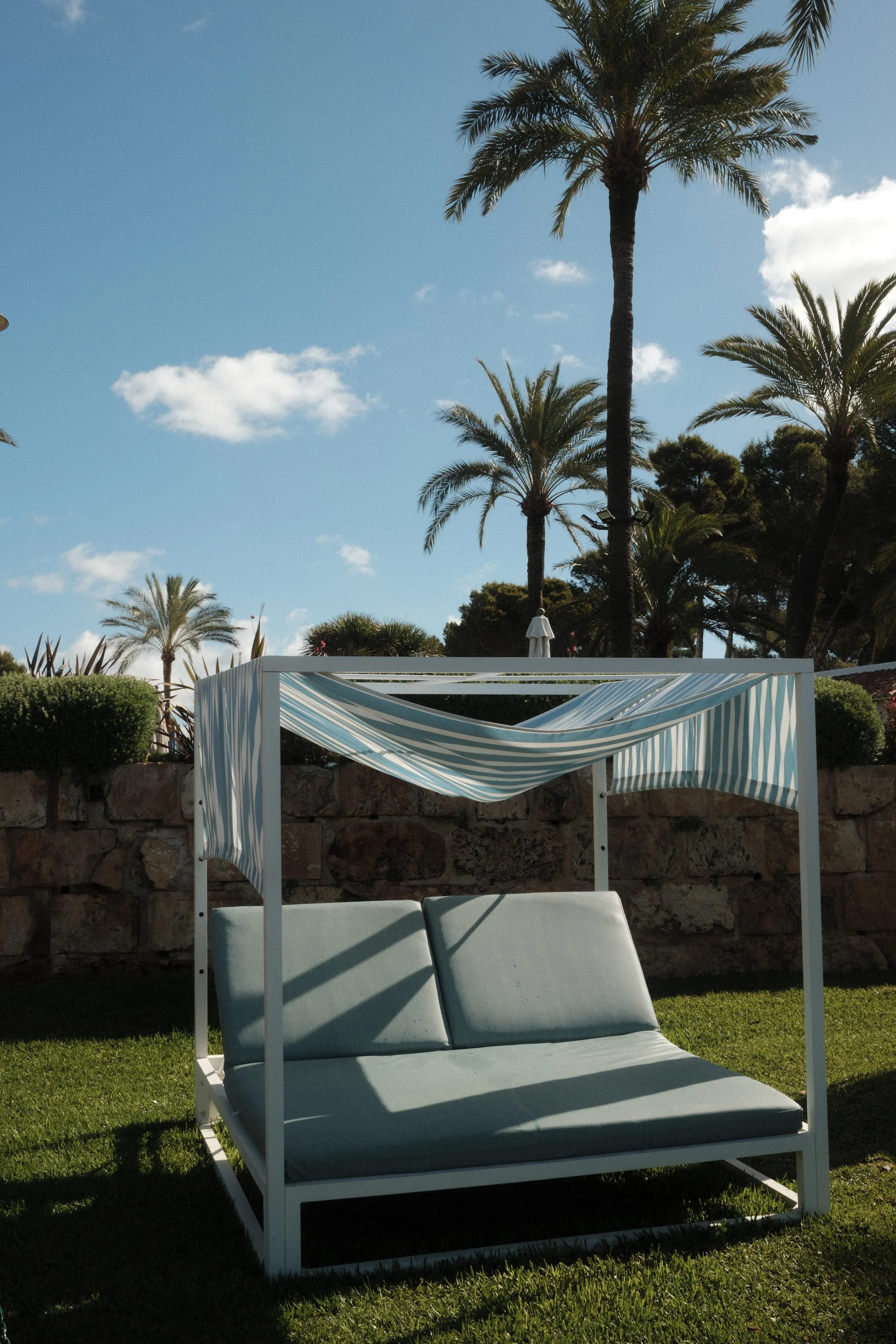 Private garden daybed surrounded by palm trees and resort greenery at Hilton Mallorca Galatzo, Mallorca, Spain