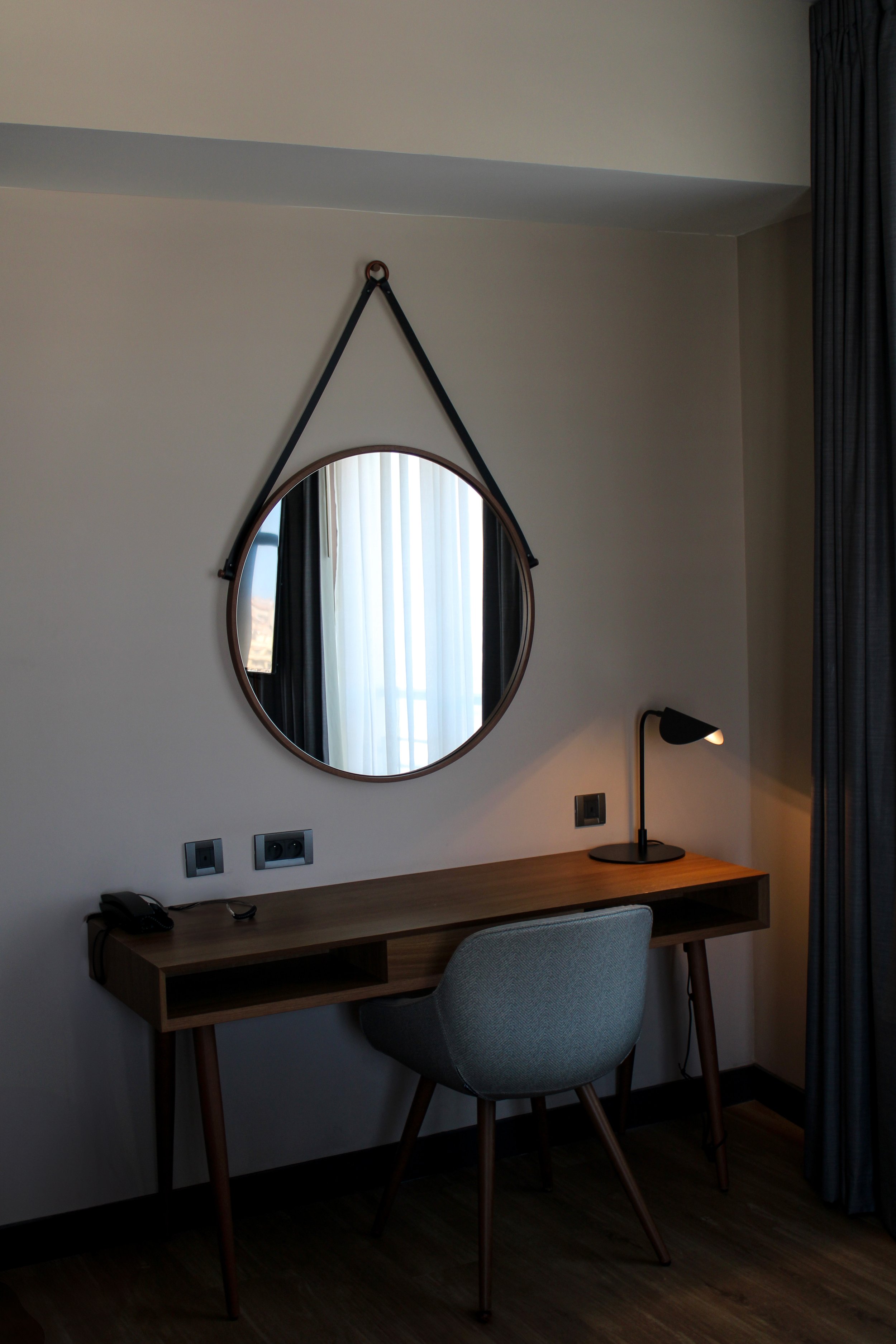 Minimalist workspace with circular mirror and contemporary wooden desk