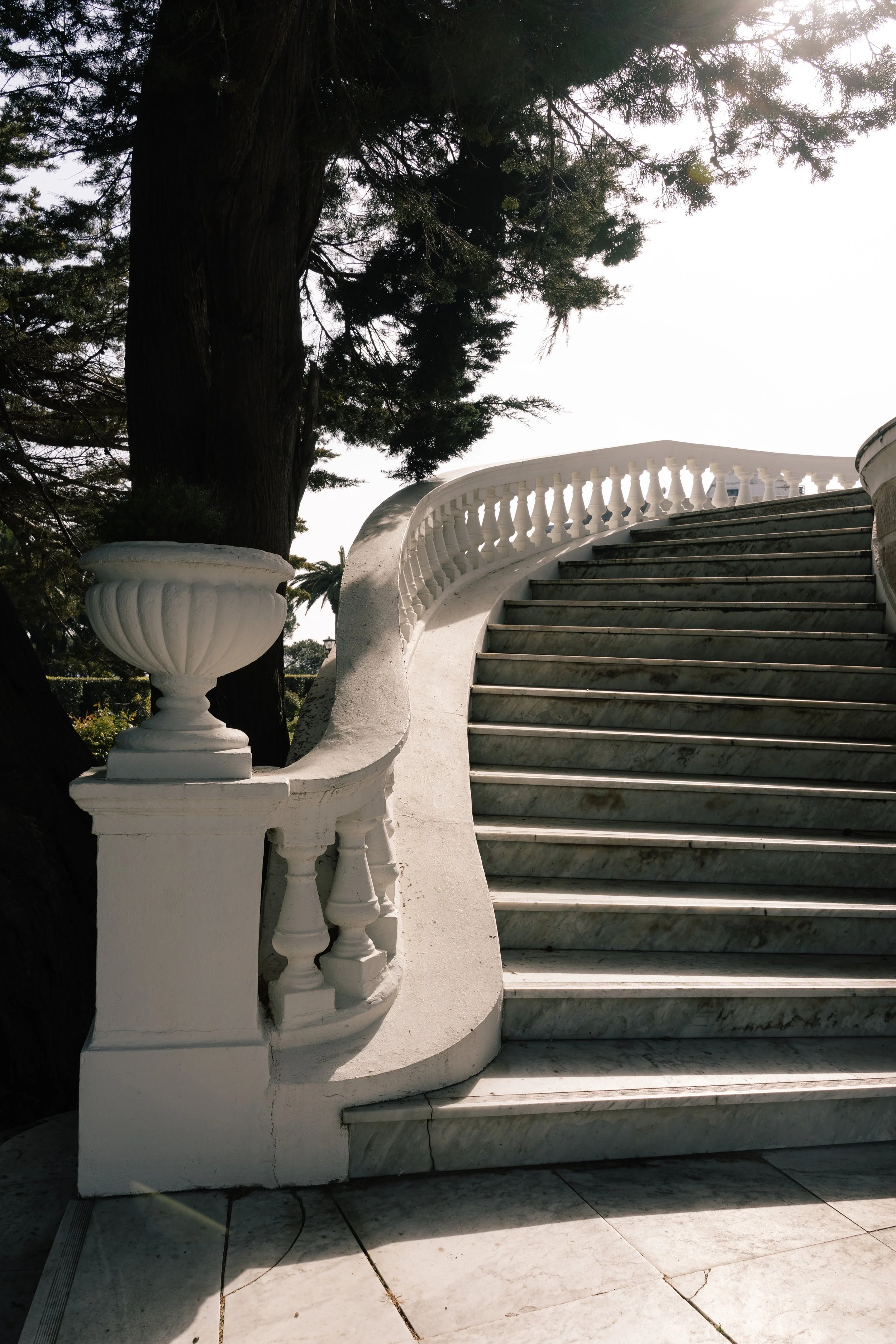 Grand marble staircase framed by elegant balustrades and mature gardens