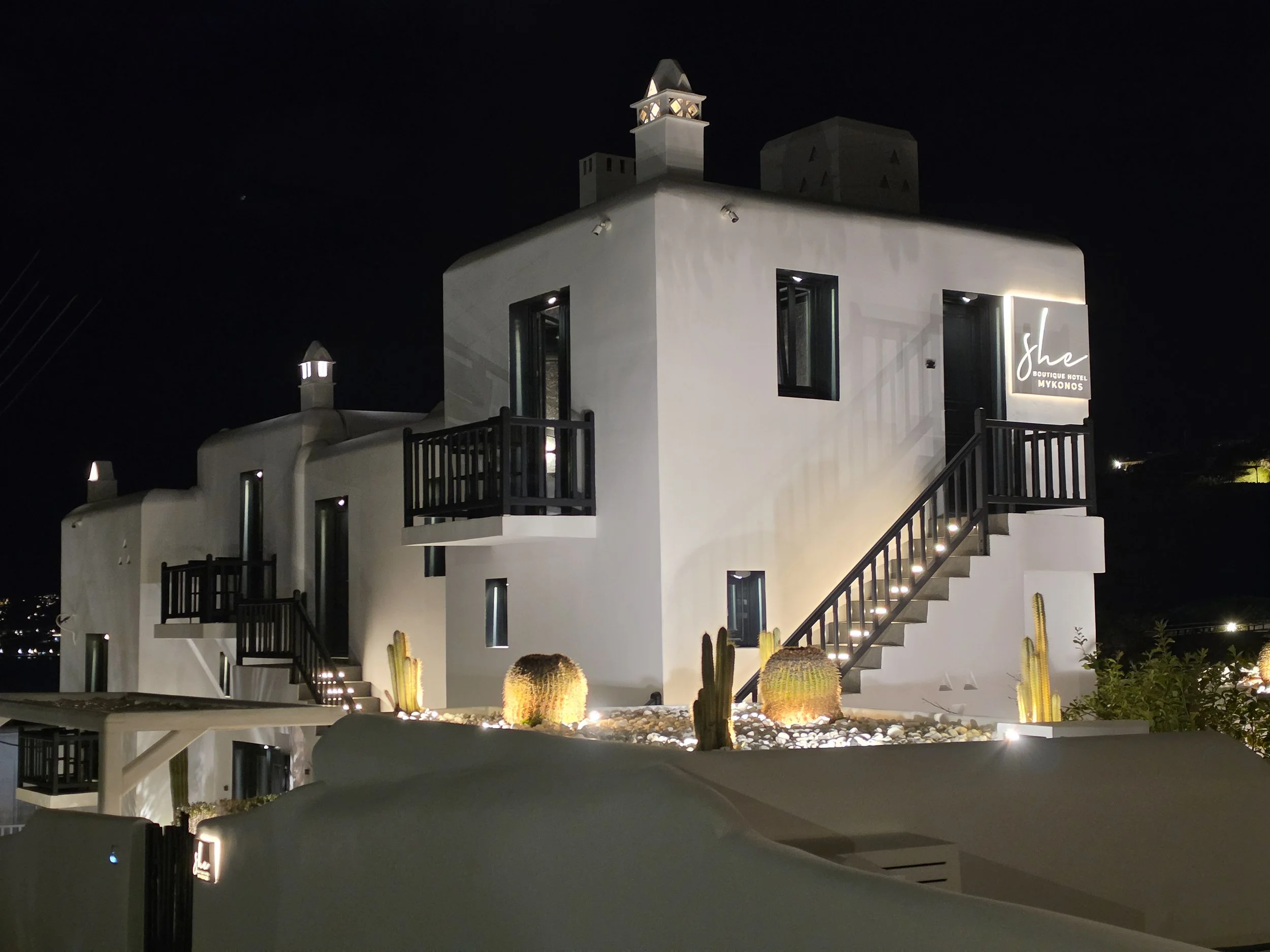 Whitewashed boutique hotel exterior illuminated at night at She Mykonos Hotel in Mykonos