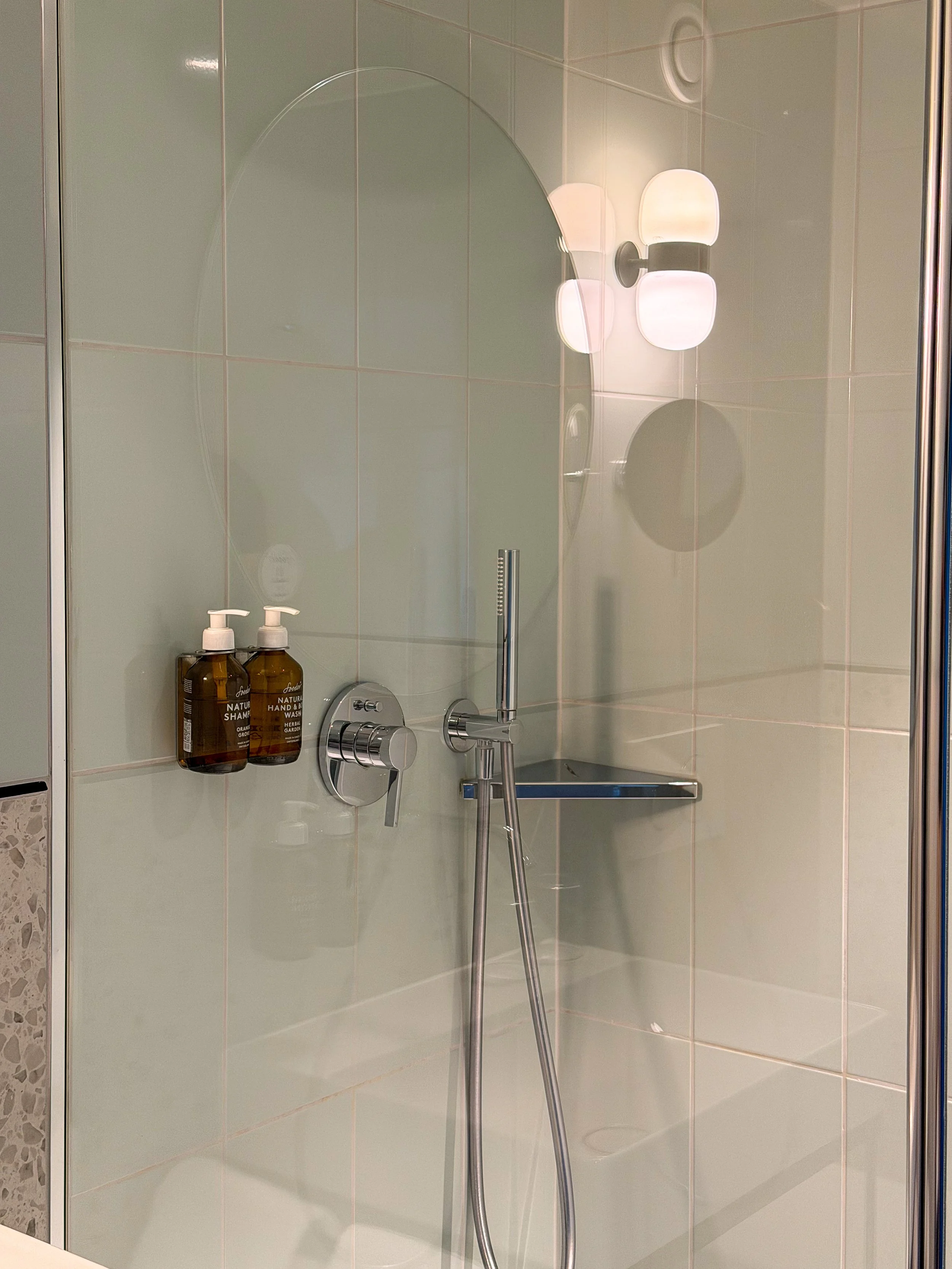 Bright walk in shower with premium amenities, elegant lighting, and modern finishes