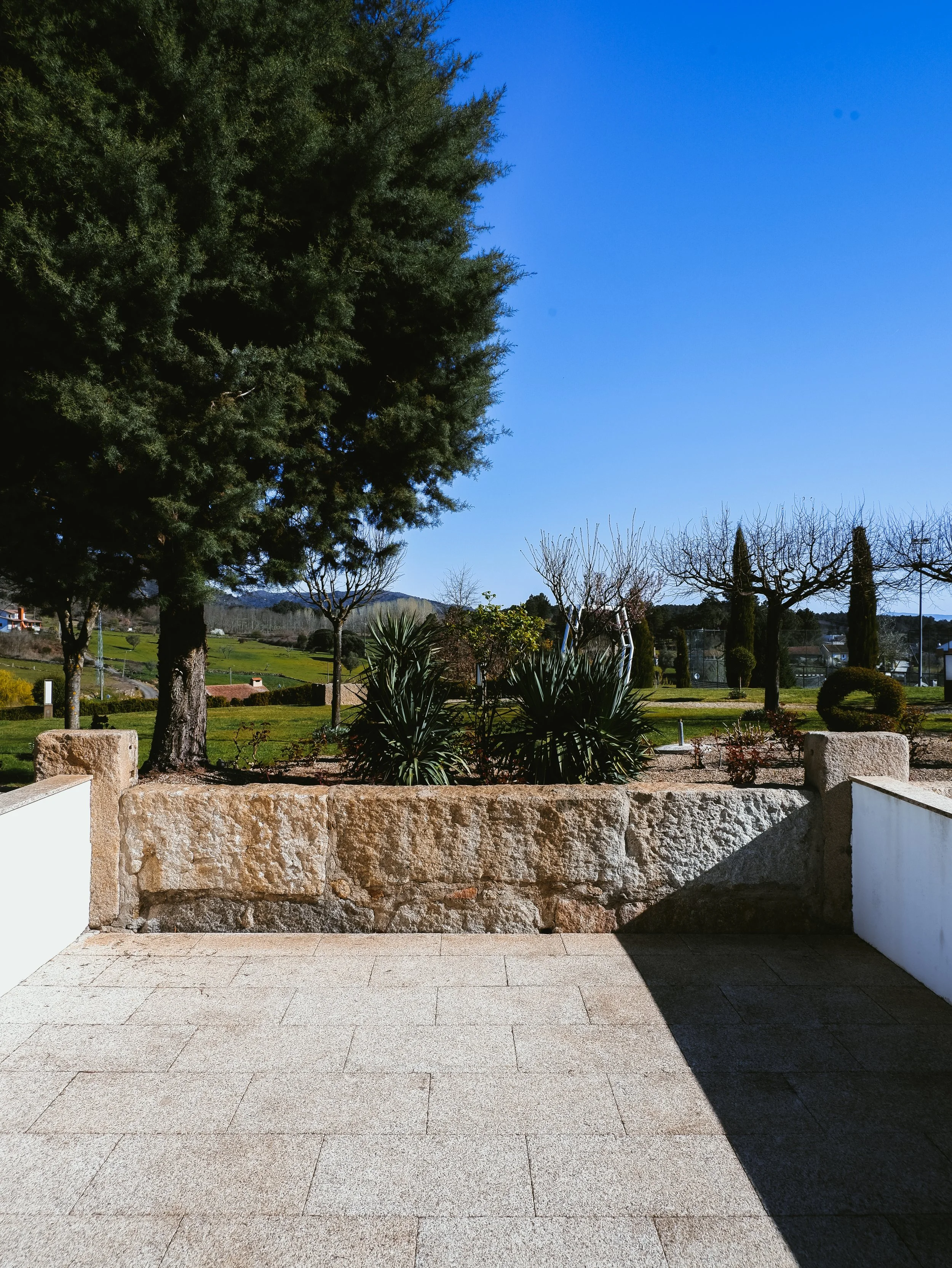 Garden terrace overlooking landscaped greenery and countryside views under clear blue skies, Casas Novas Countryside Hotel Spa & Events – Chaves, Portugal.