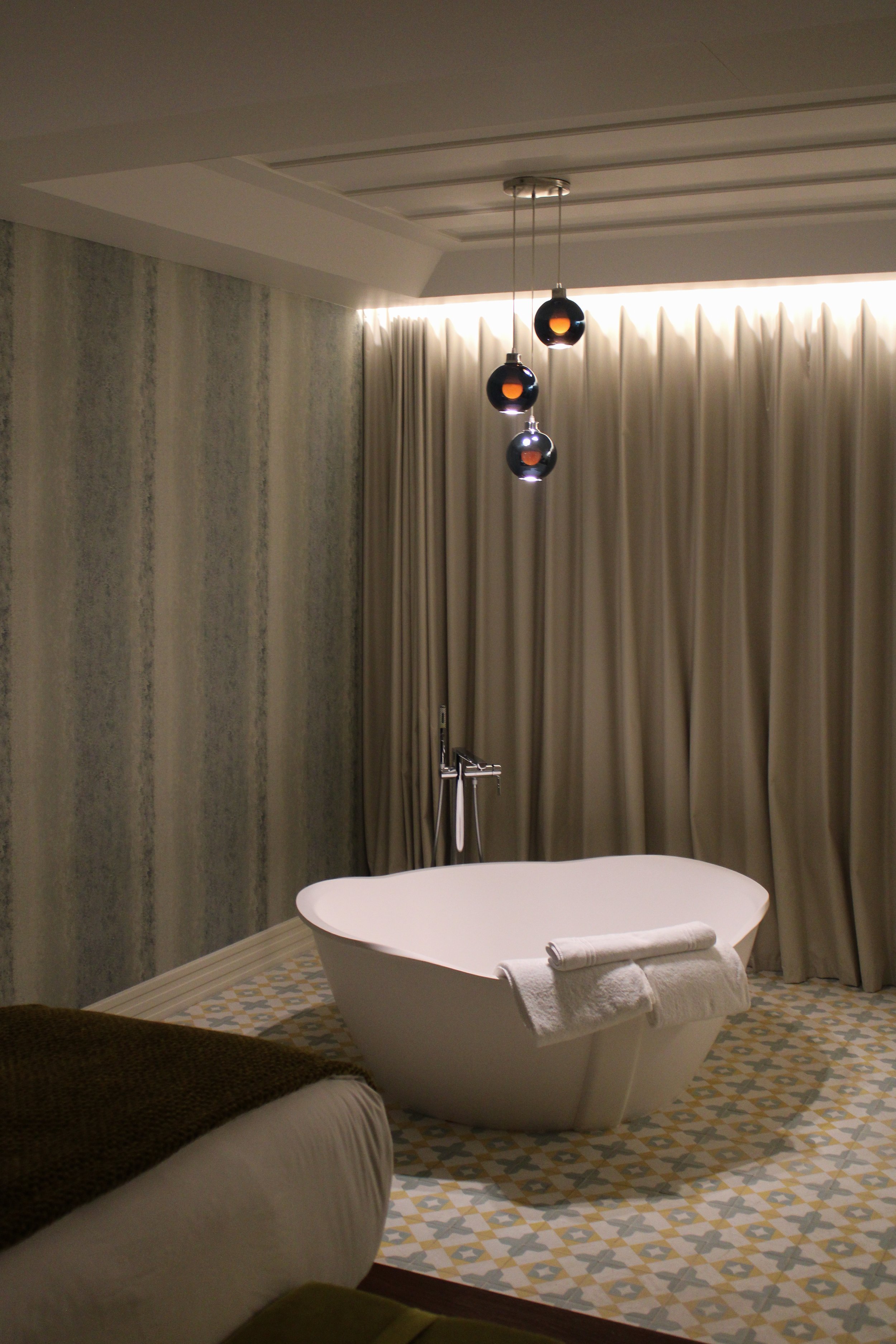 Luxury suite featuring a freestanding bathtub, designer lighting, and elegant contemporary interiors