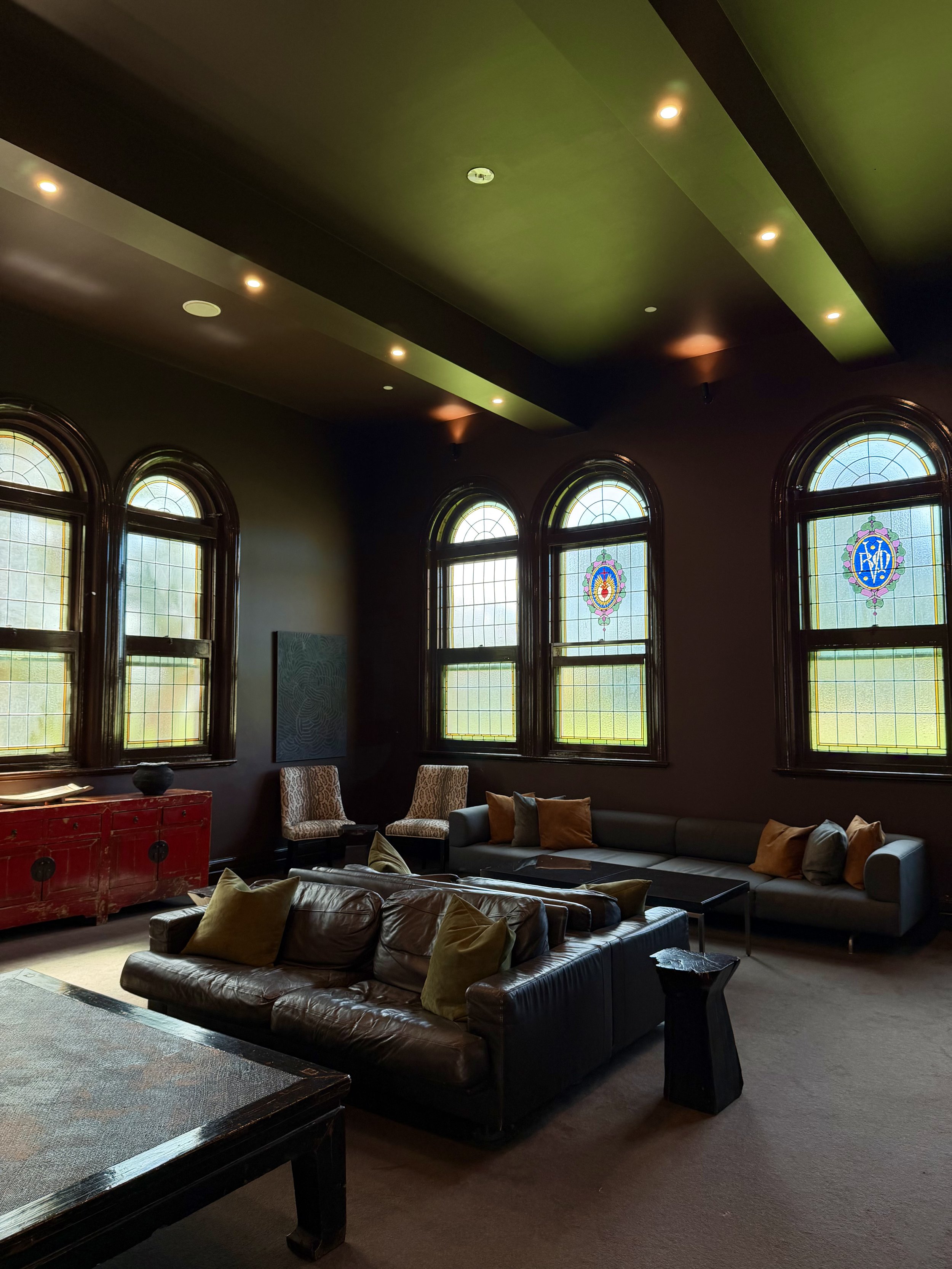Historic lounge featuring leather sofas, decorative stained glass windows, dark walls, and elegant furnishings