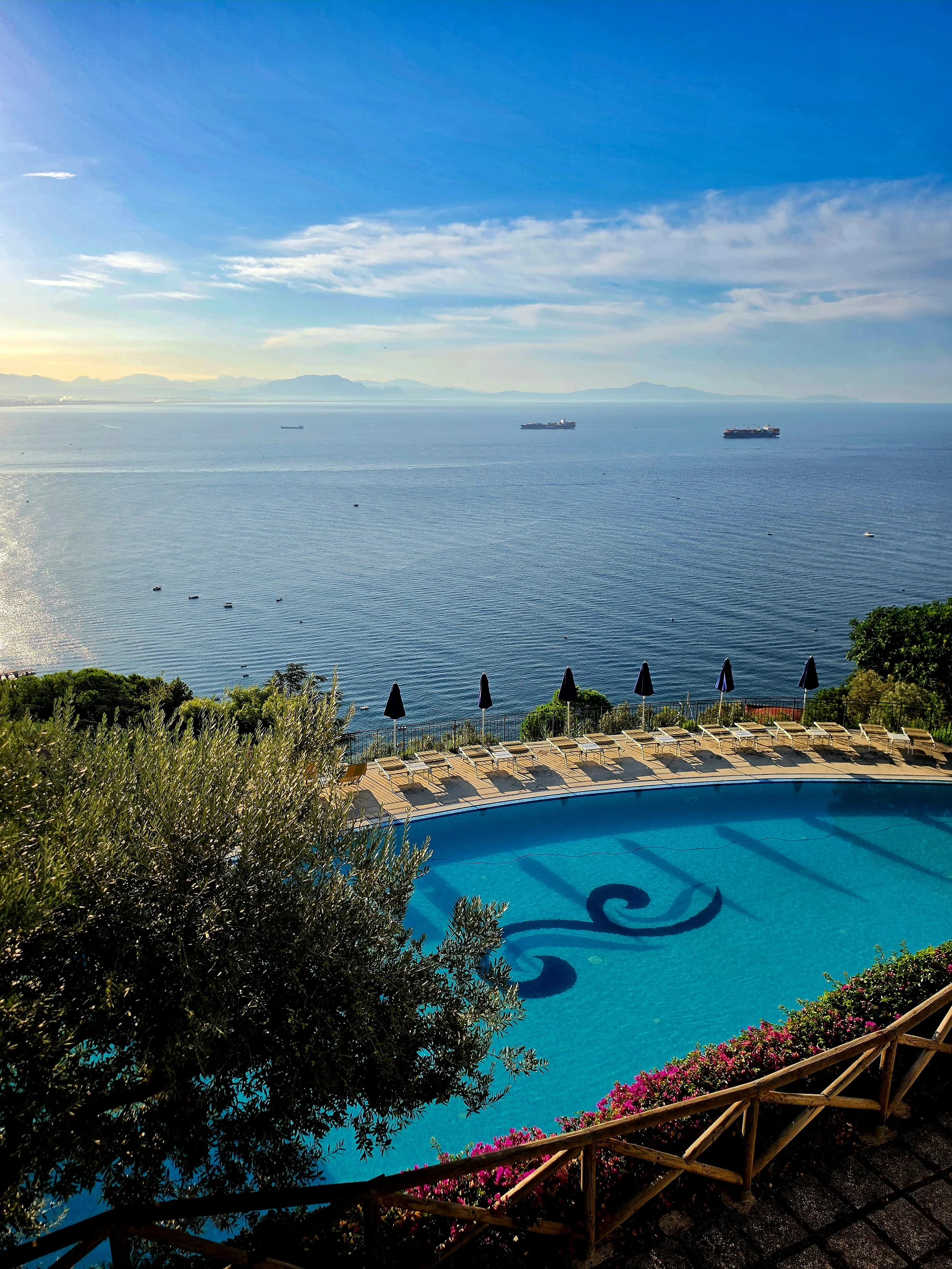 Outdoor swimming pool overlooking the Gulf of Salerno with sun loungers and Mediterranean gardens