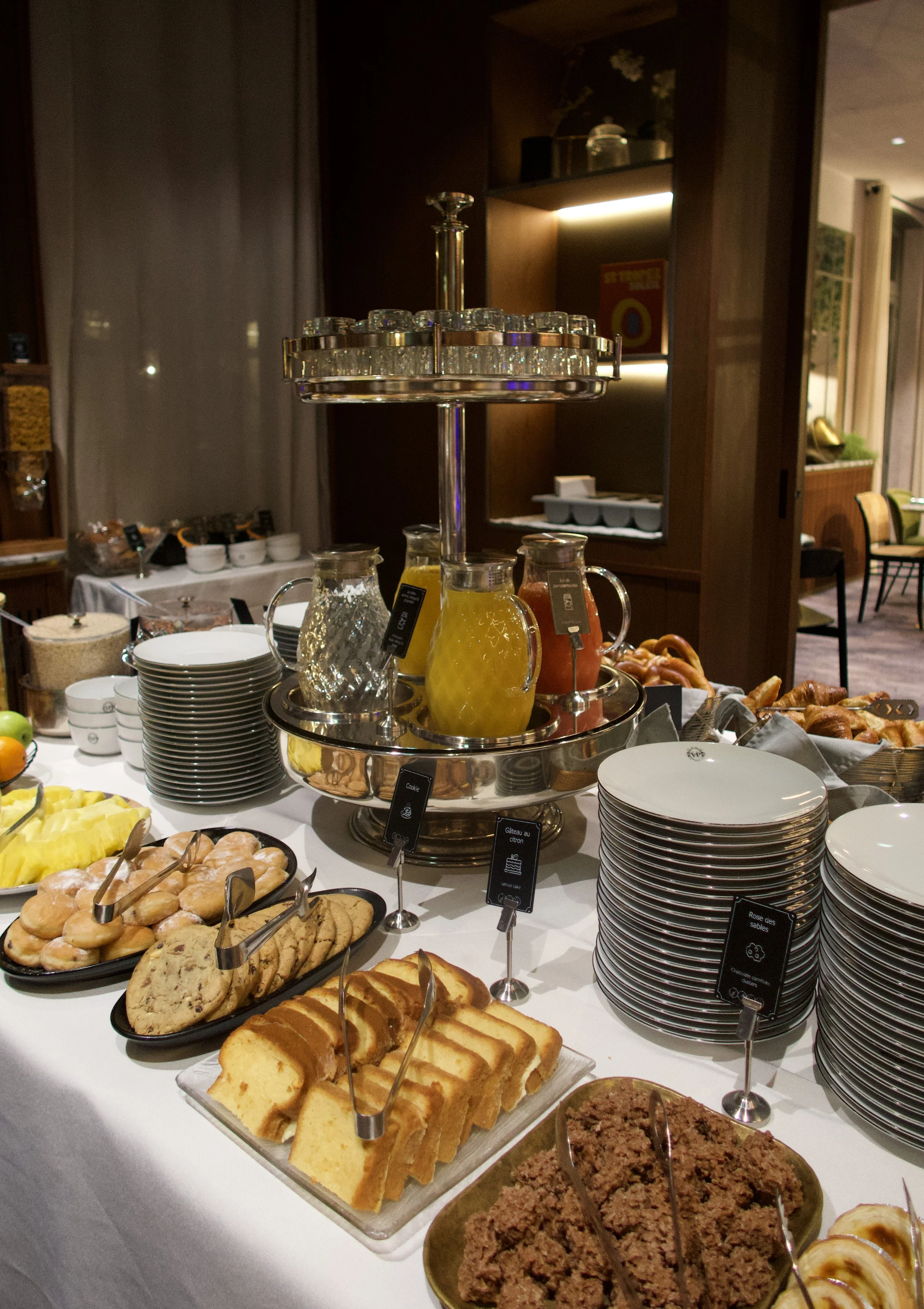 Breakfast buffet with fresh pastries, sliced cakes, juices, and neatly stacked porcelain plates, Victoria Palace Hotel – Paris, France.