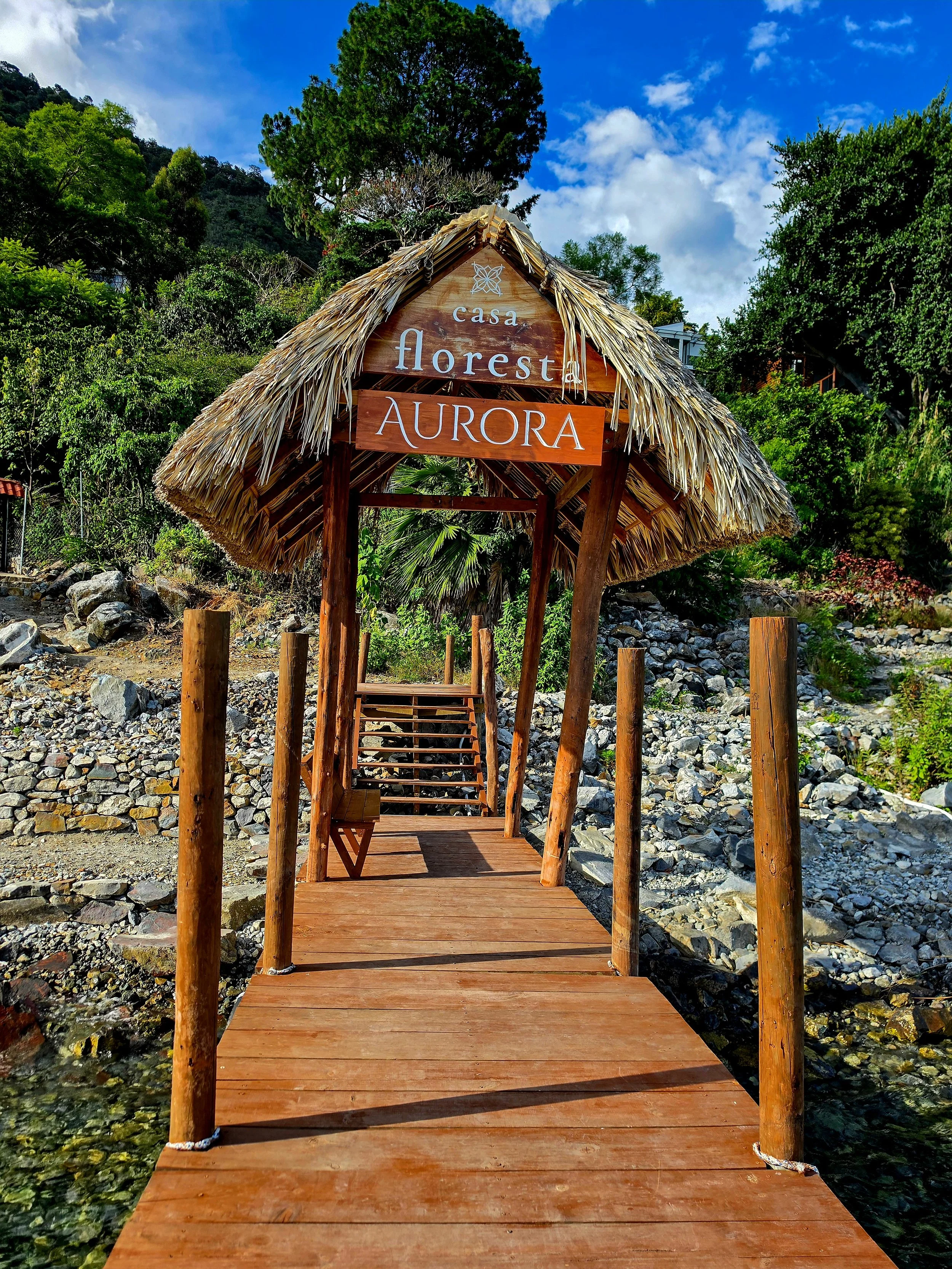 Wooden lakeside dock with a traditional thatched entrance surrounded by nature