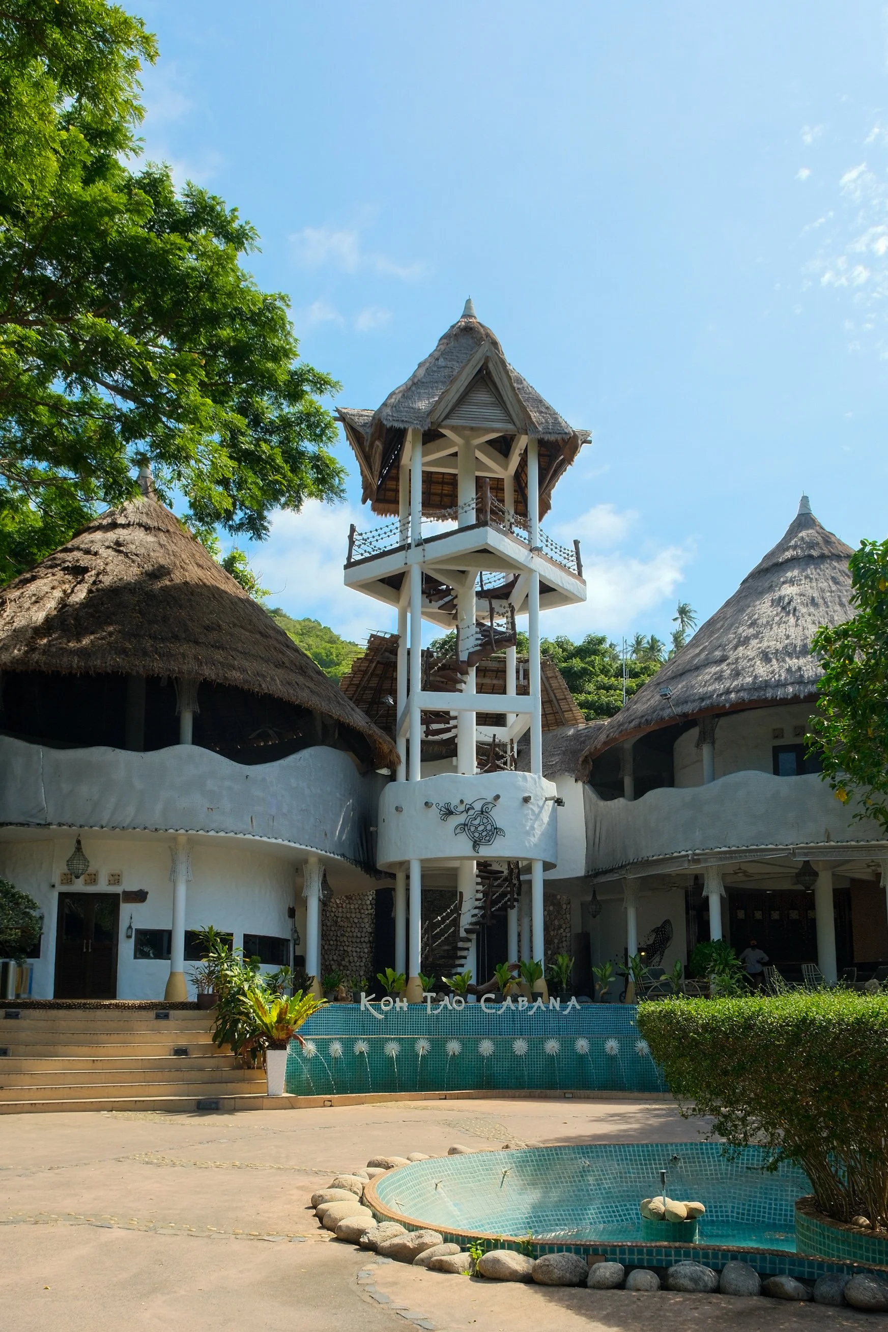 Distinctive thatched-roof architecture surrounded by tropical greenery beneath a clear blue sky