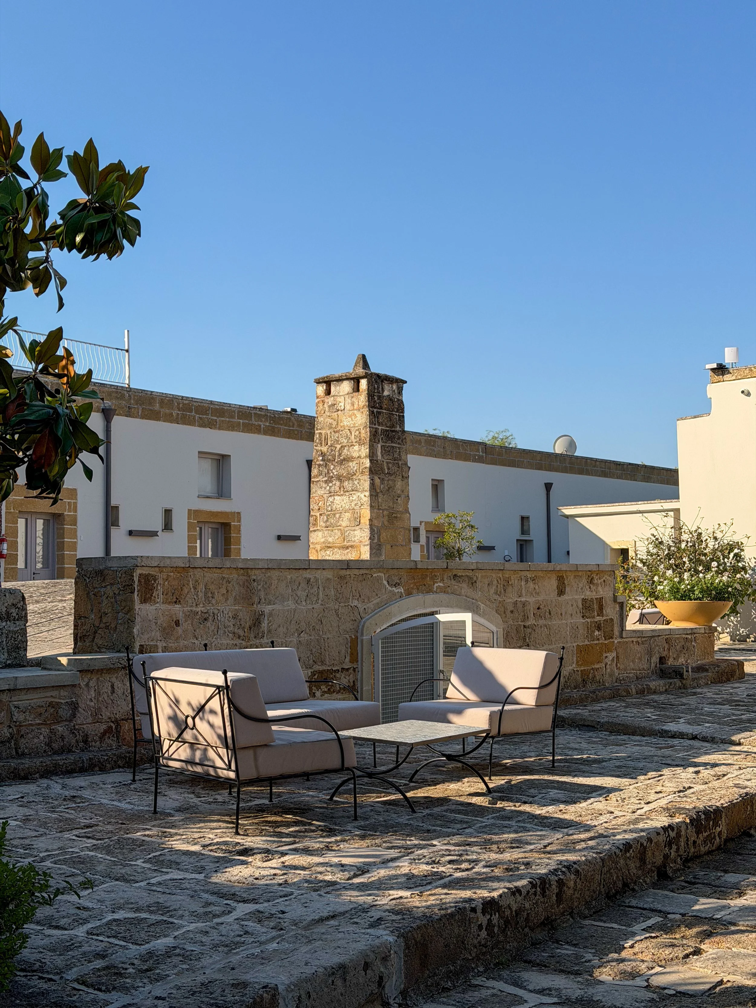 Outdoor lounge area surrounded by historic stone buildings and warm Mediterranean light at Tenuta Monacelli Lecce