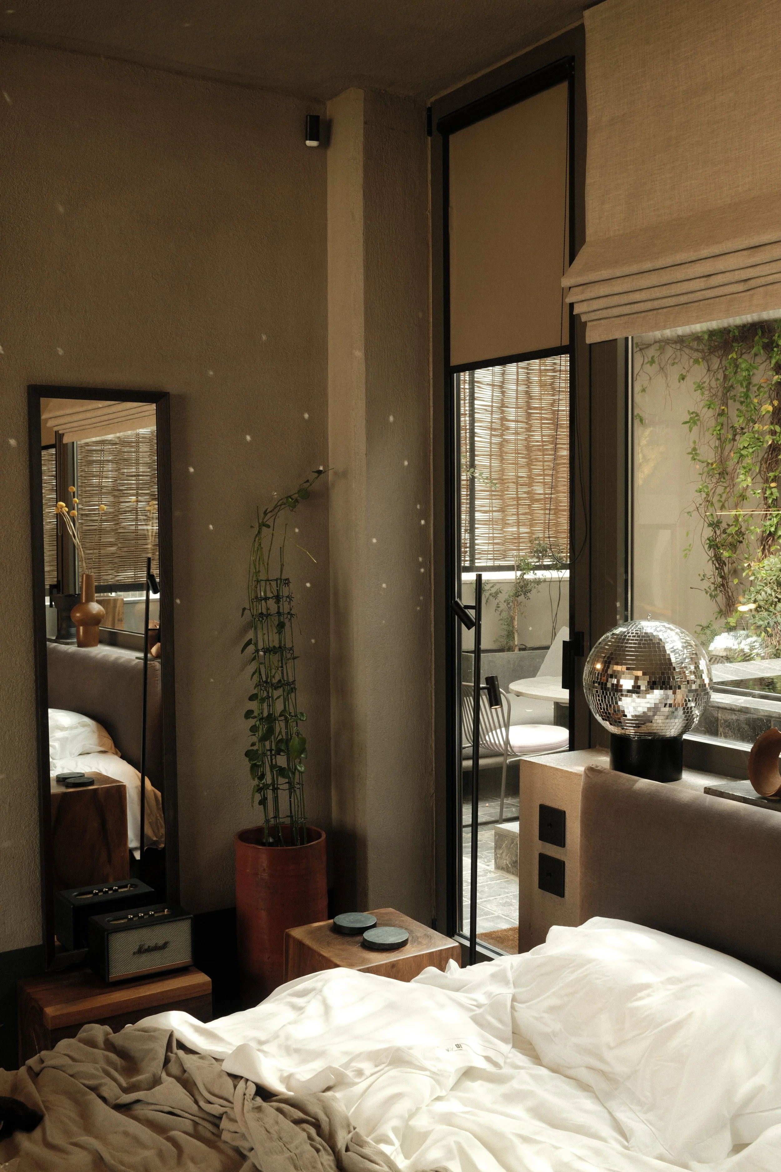 Contemporary bedroom with natural textures, warm lighting, courtyard views, and artistic details