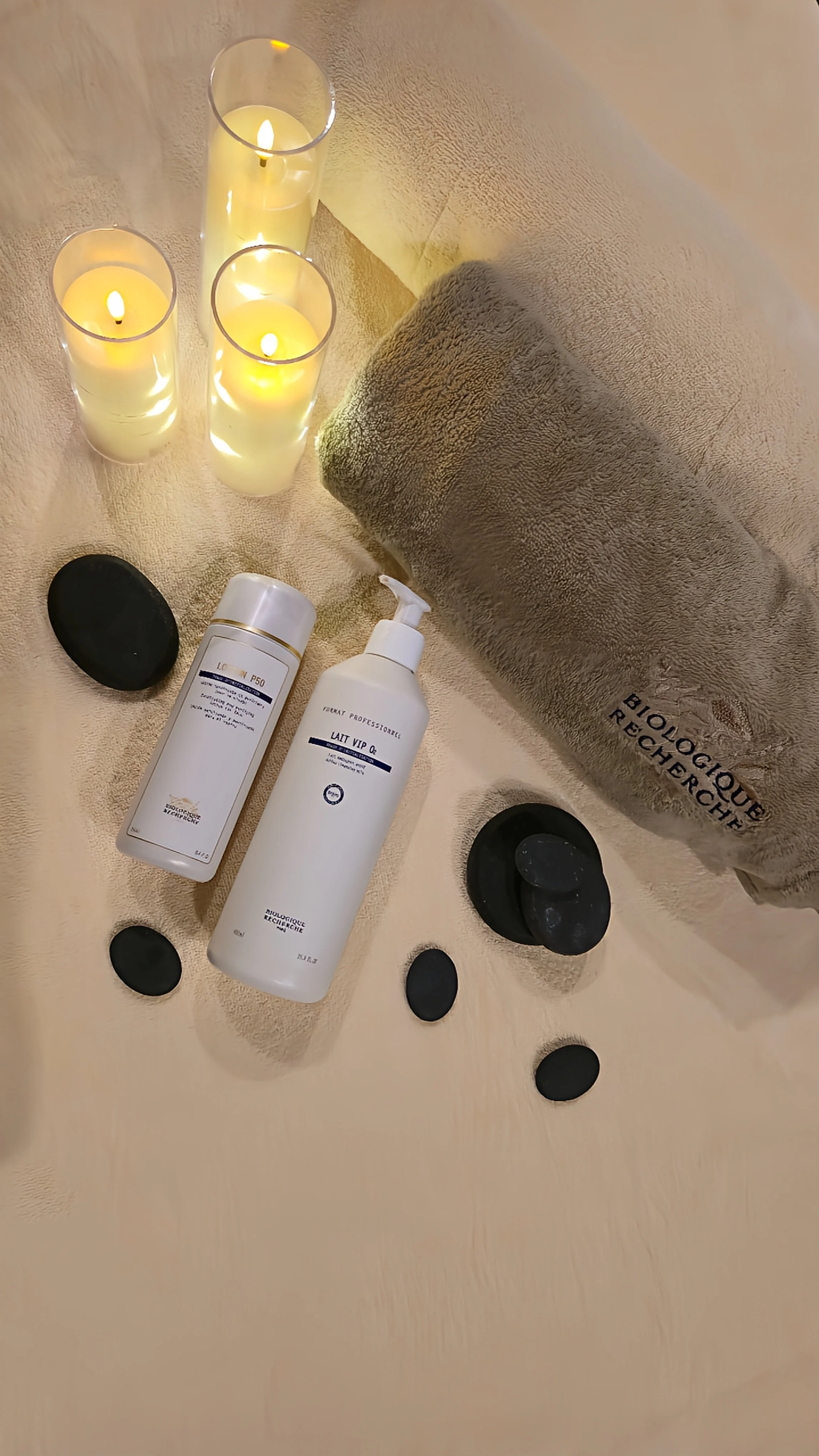 Spa treatment setup with candles, hot stones, towels, and professional skincare products