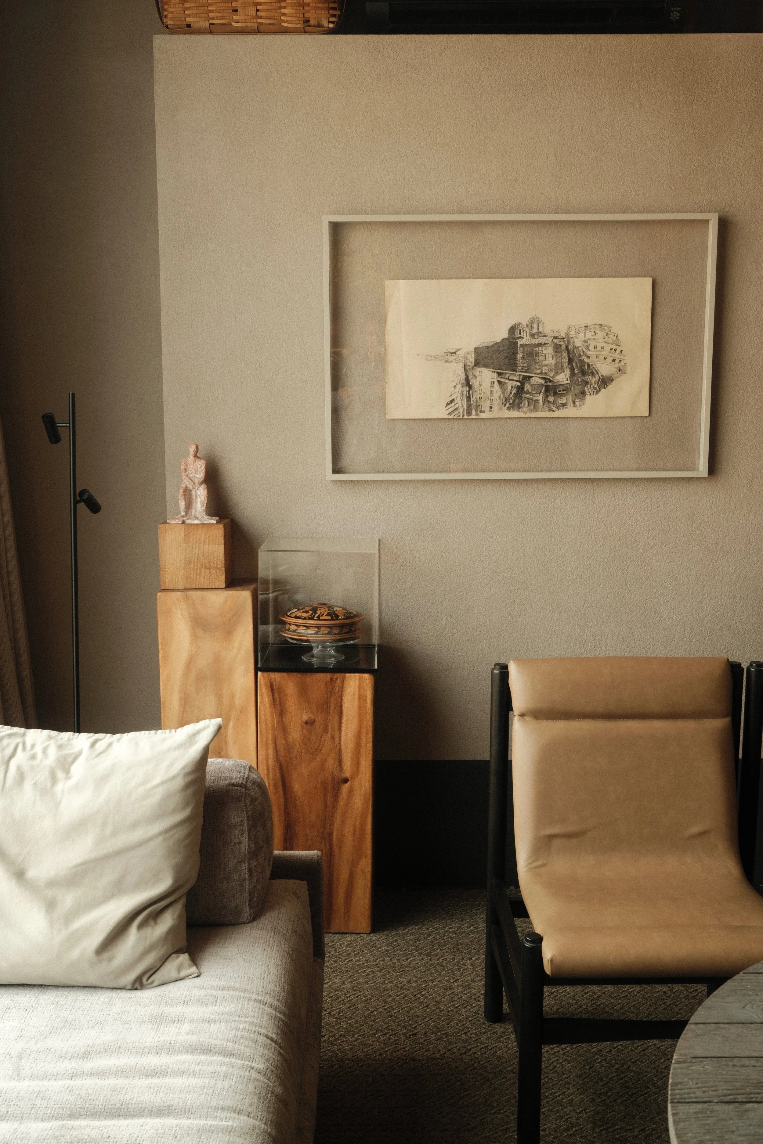 Minimalist suite lounge with warm wood furnishings, curated artwork, and sculptural decorative pieces