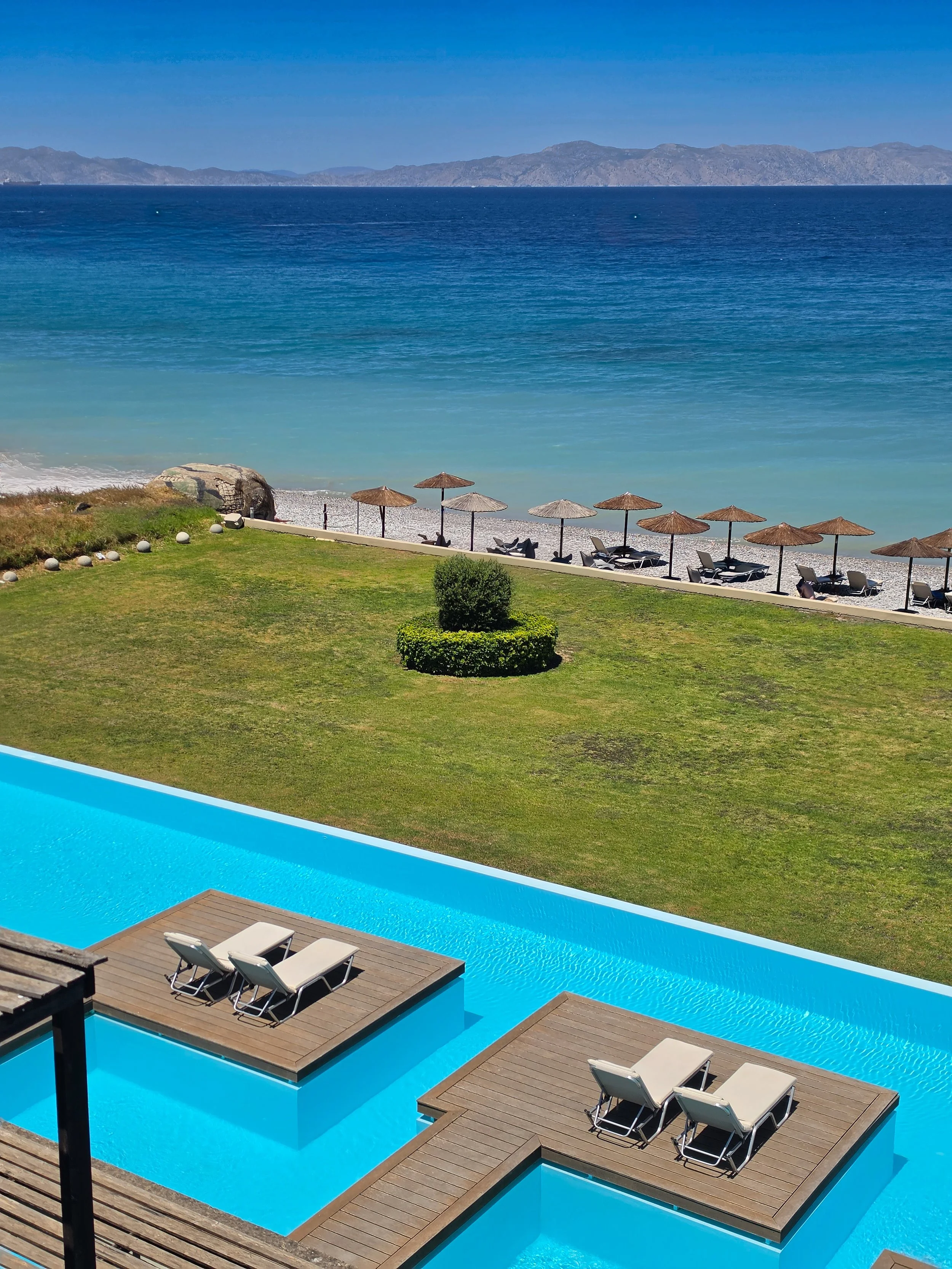 Infinity pools flowing seamlessly towards the Aegean coastline