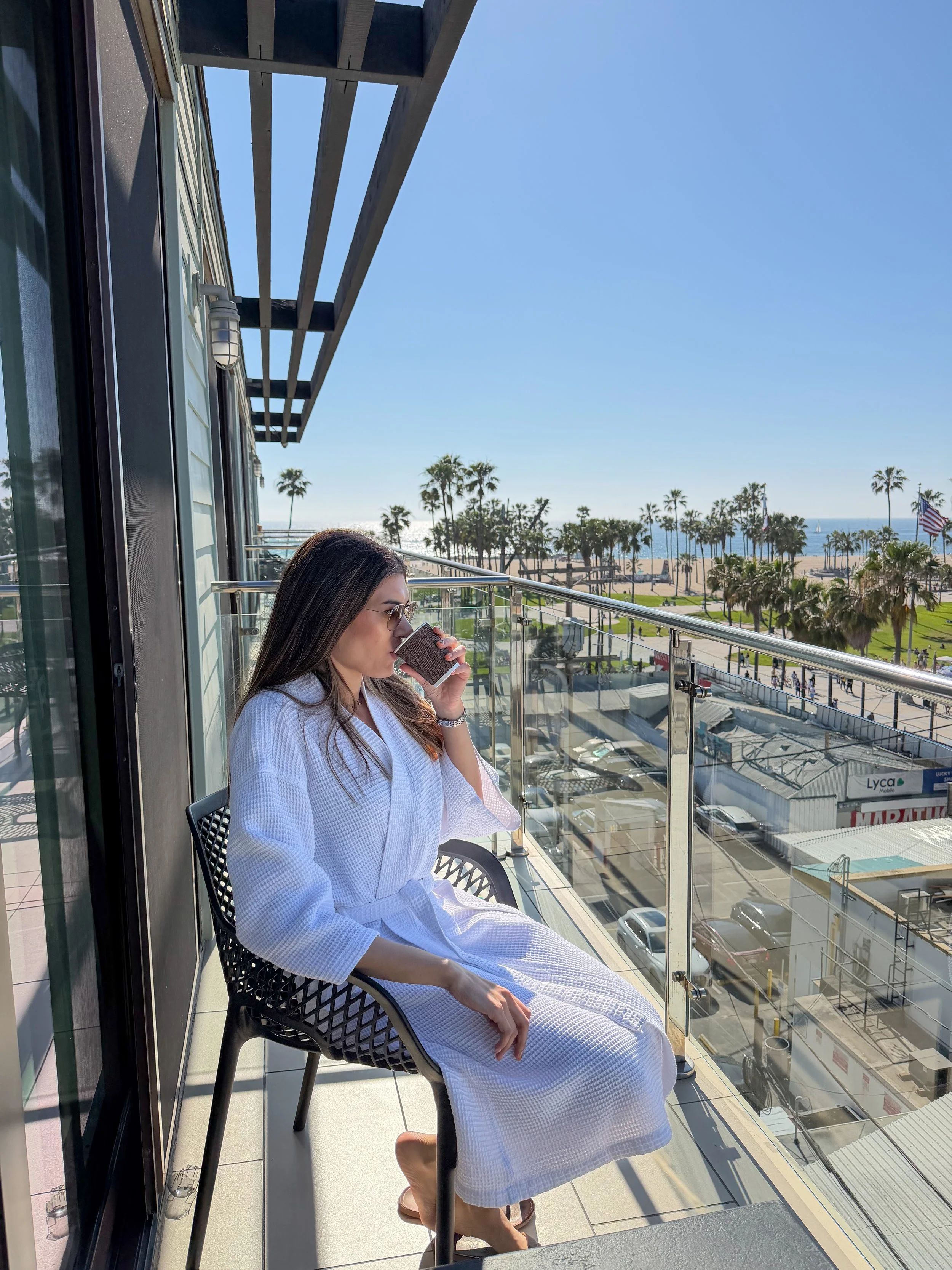 Morning coffee on a private balcony overlooking Venice Beach, palm trees, and the Pacific coastline