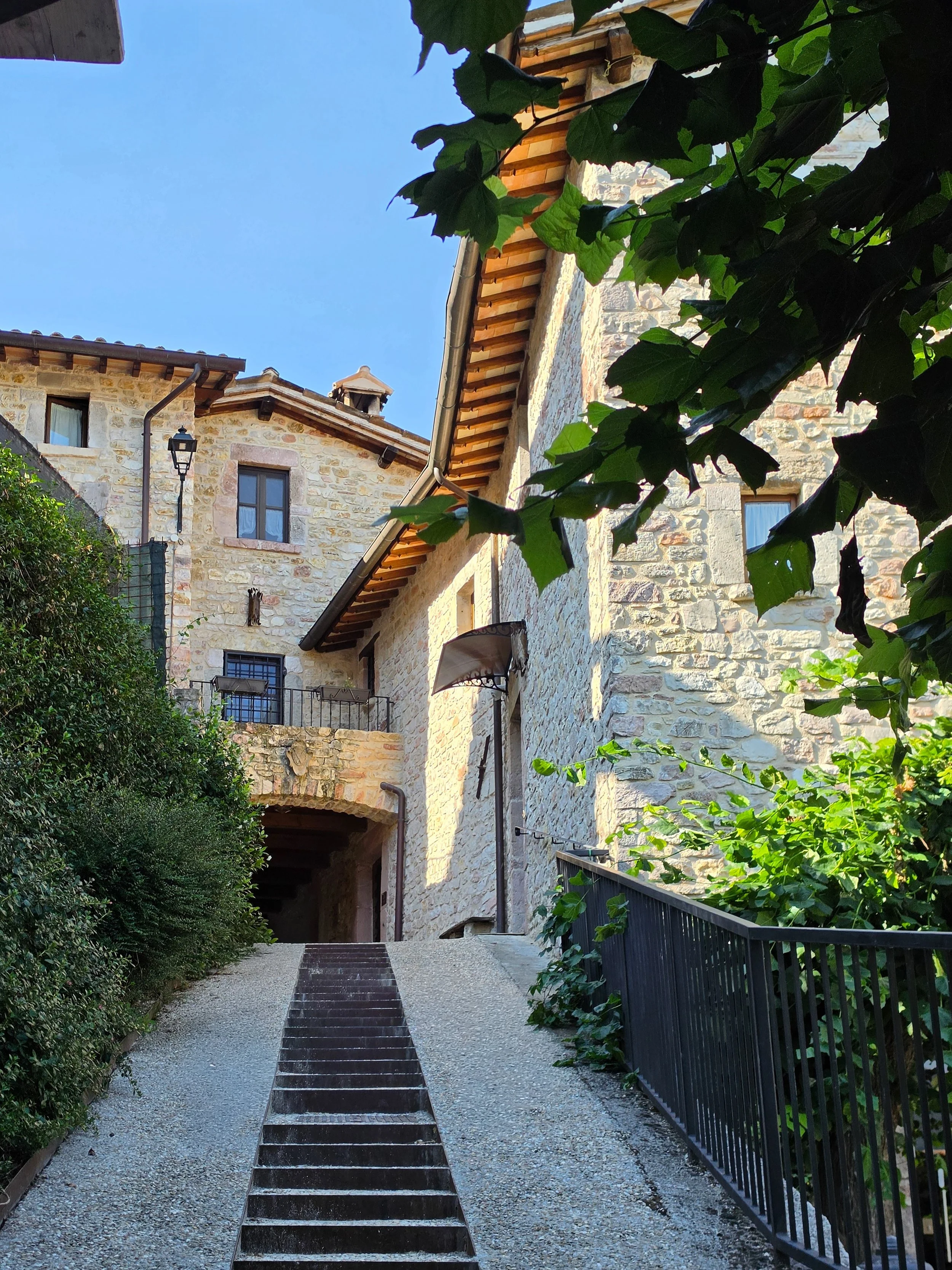 Stone pathway leading through the beautifully restored medieval village surrounded by greenery