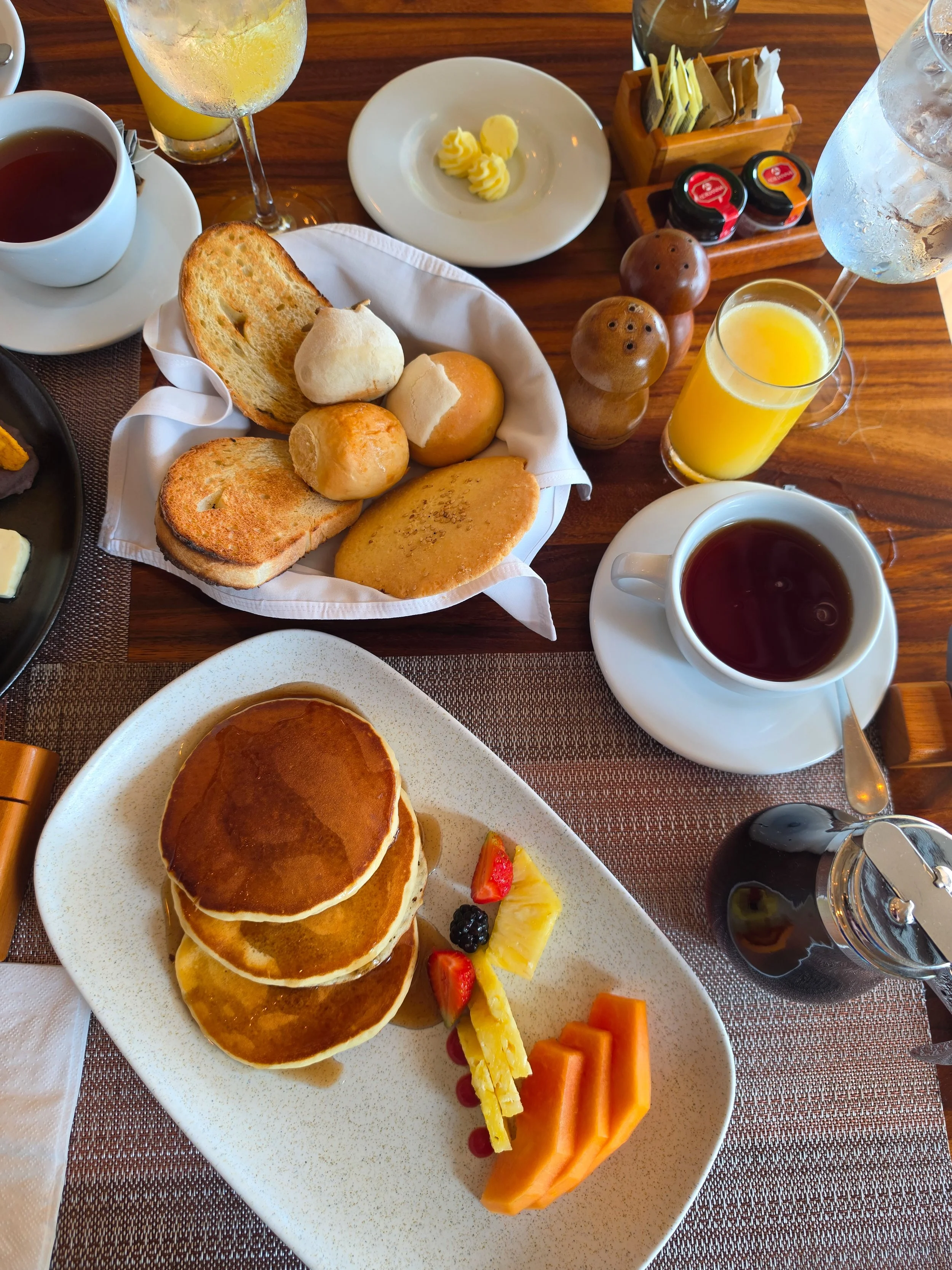 Freshly prepared breakfast with pancakes, tropical fruit, pastries, and fresh juices