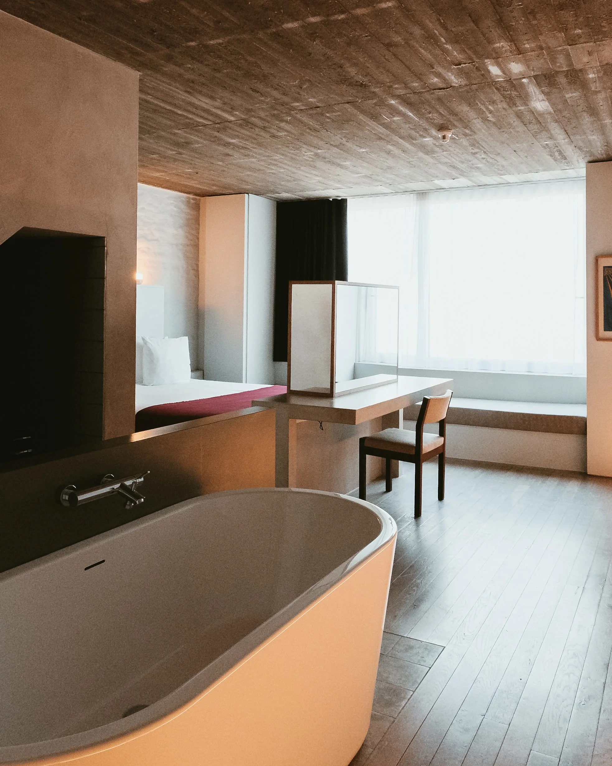 Spacious suite featuring a freestanding bathtub, minimalist interiors, and abundant natural light