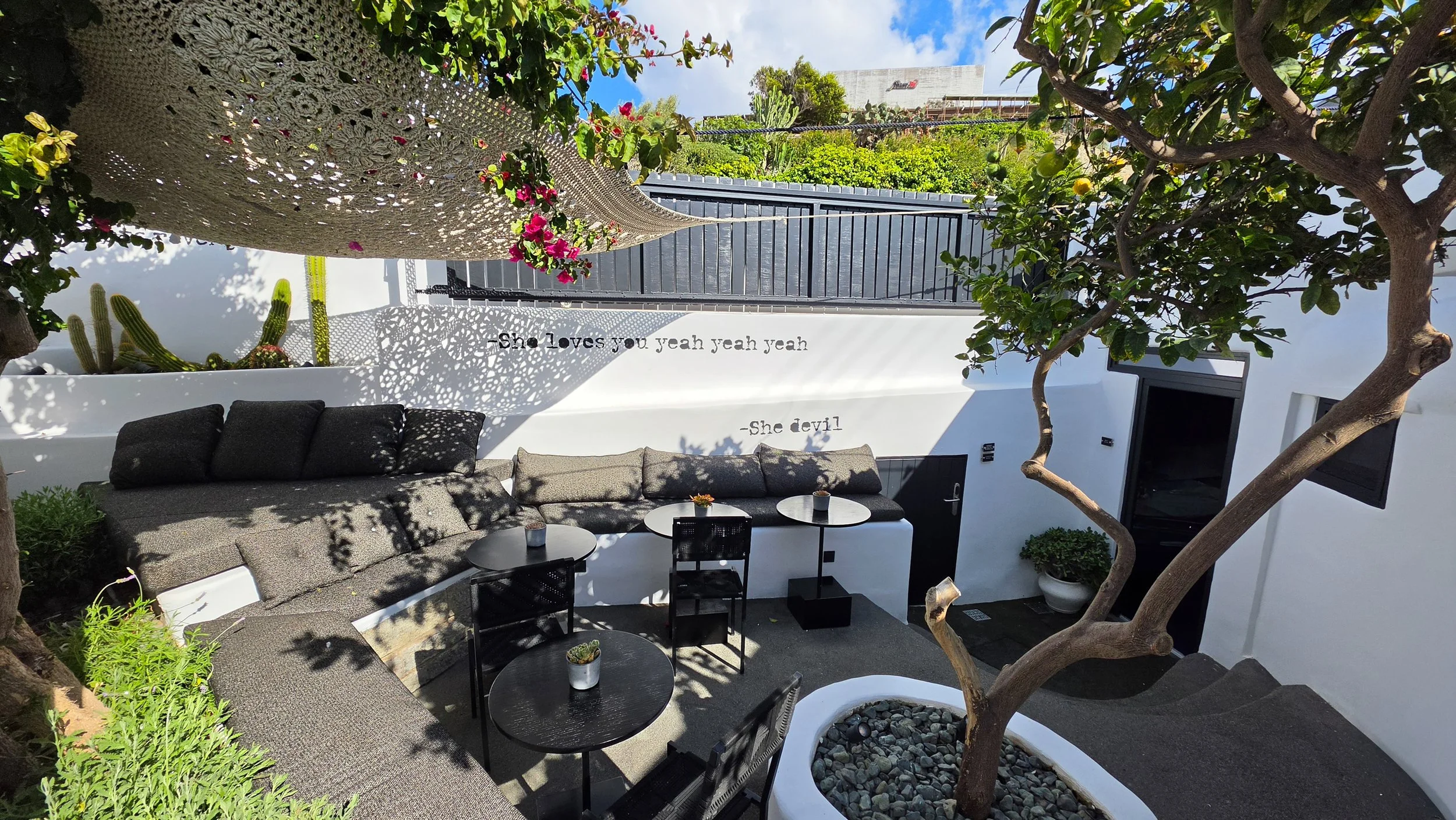 Minimalist outdoor lounge surrounded by Mediterranean greenery at She Mykonos Hotel in Mykonos