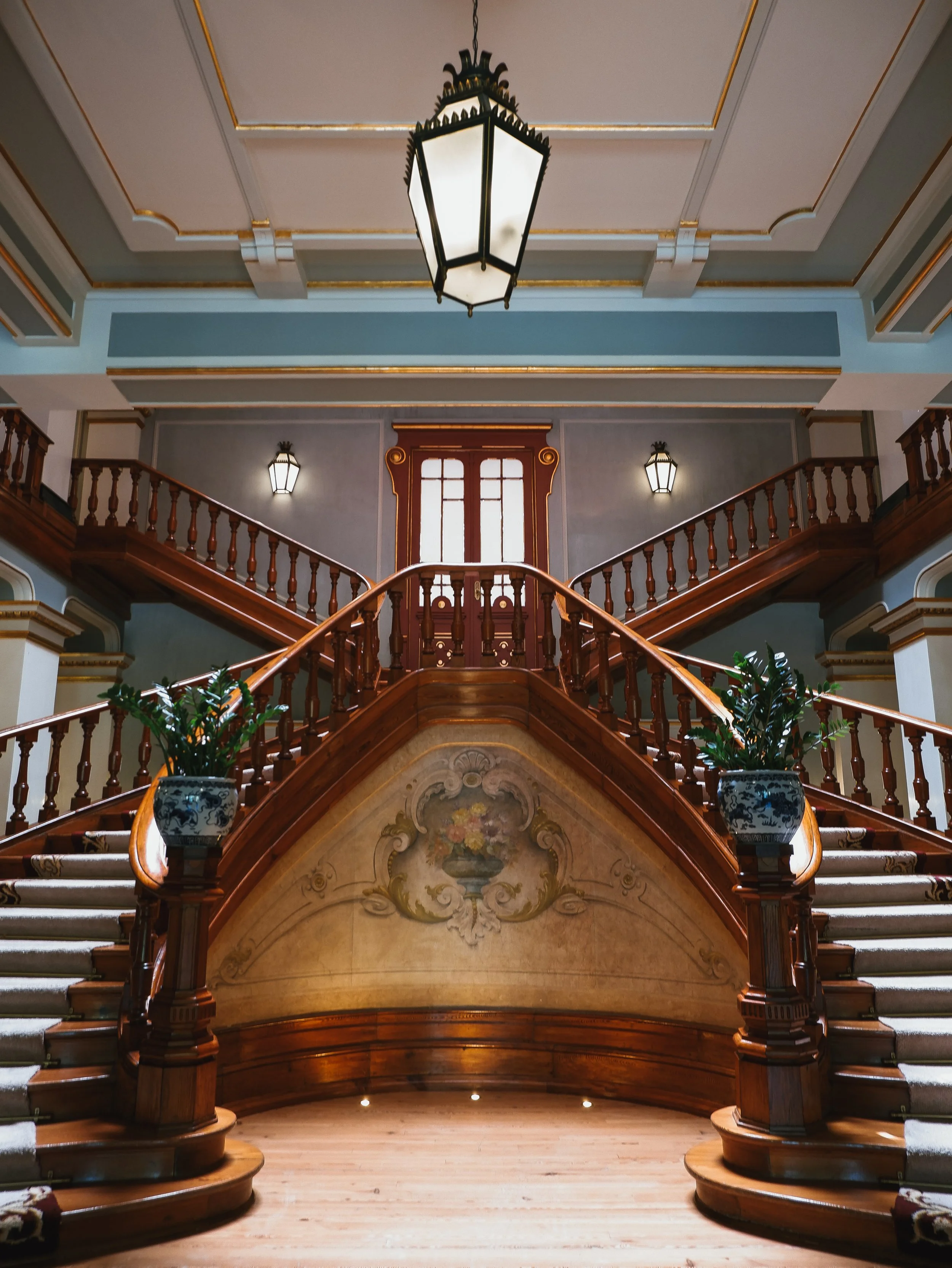 Historic grand staircase with handcrafted wood balustrades, elegant arches, and timeless Portuguese architecture