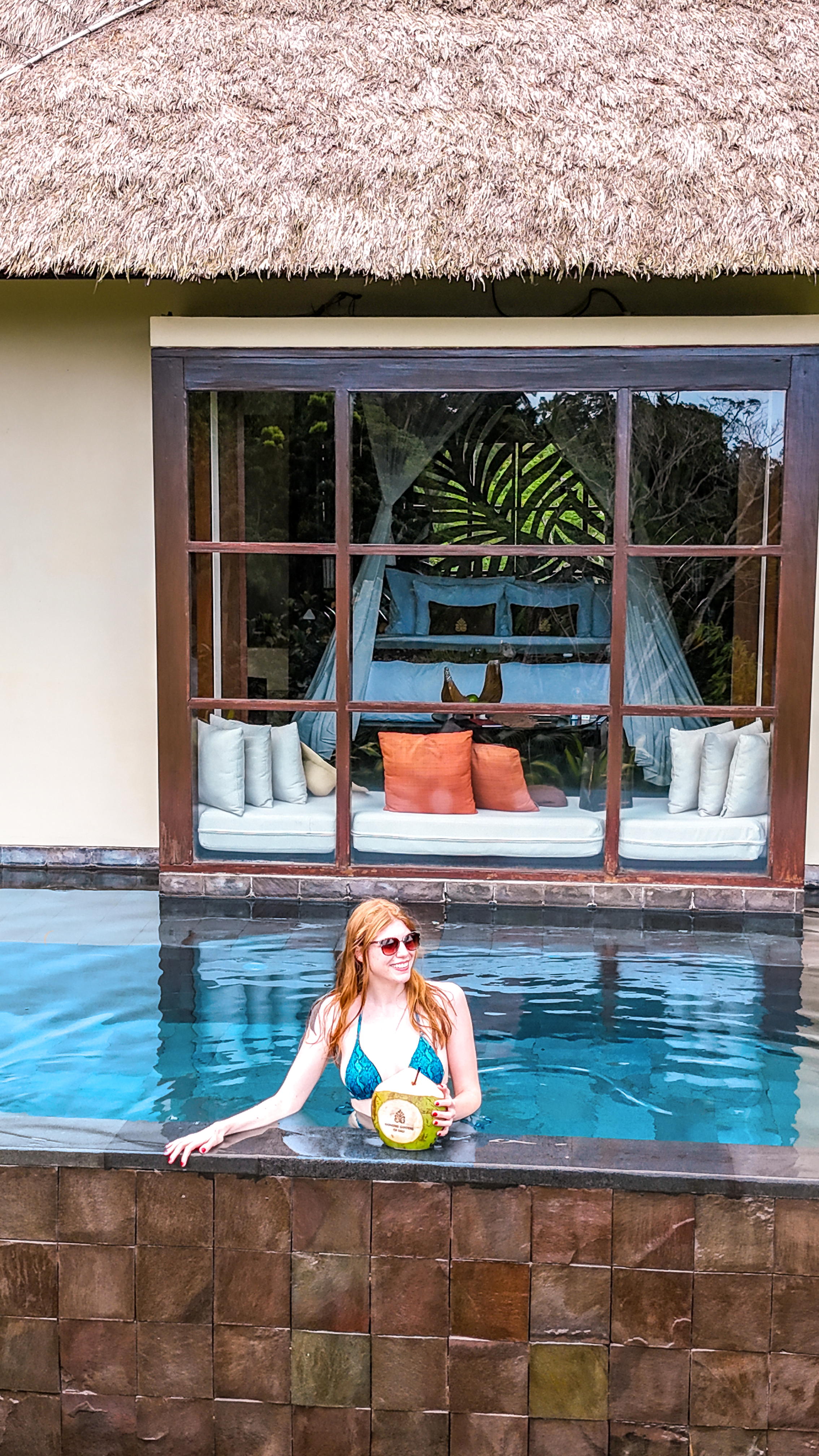 A guest relaxes in a private plunge pool beside a luxury villa surrounded by lush tropical gardens