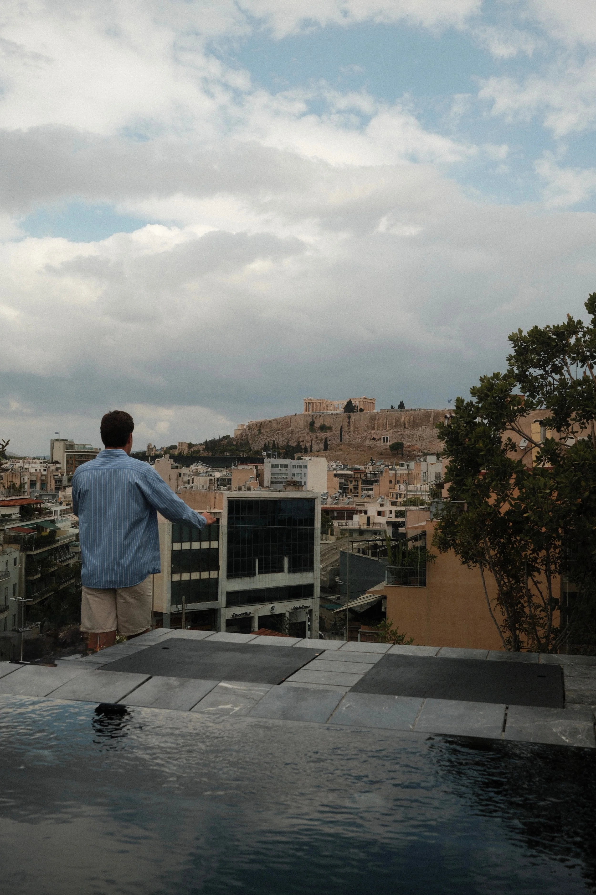 Guest overlooking the Athens skyline and Acropolis from a private rooftop plunge pool