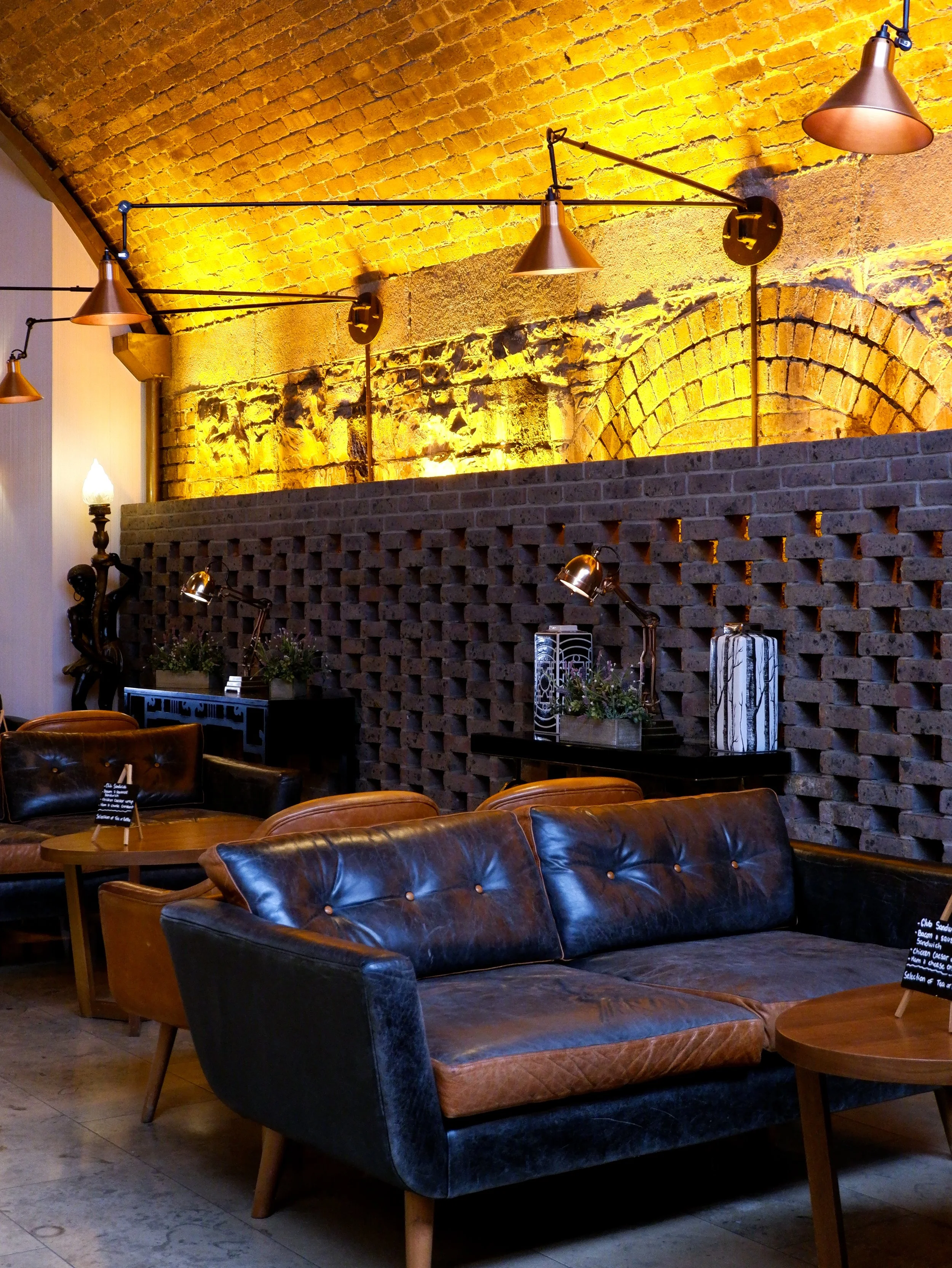 Cozy lounge featuring vintage leather sofas, exposed brick arches, and warm industrial lighting