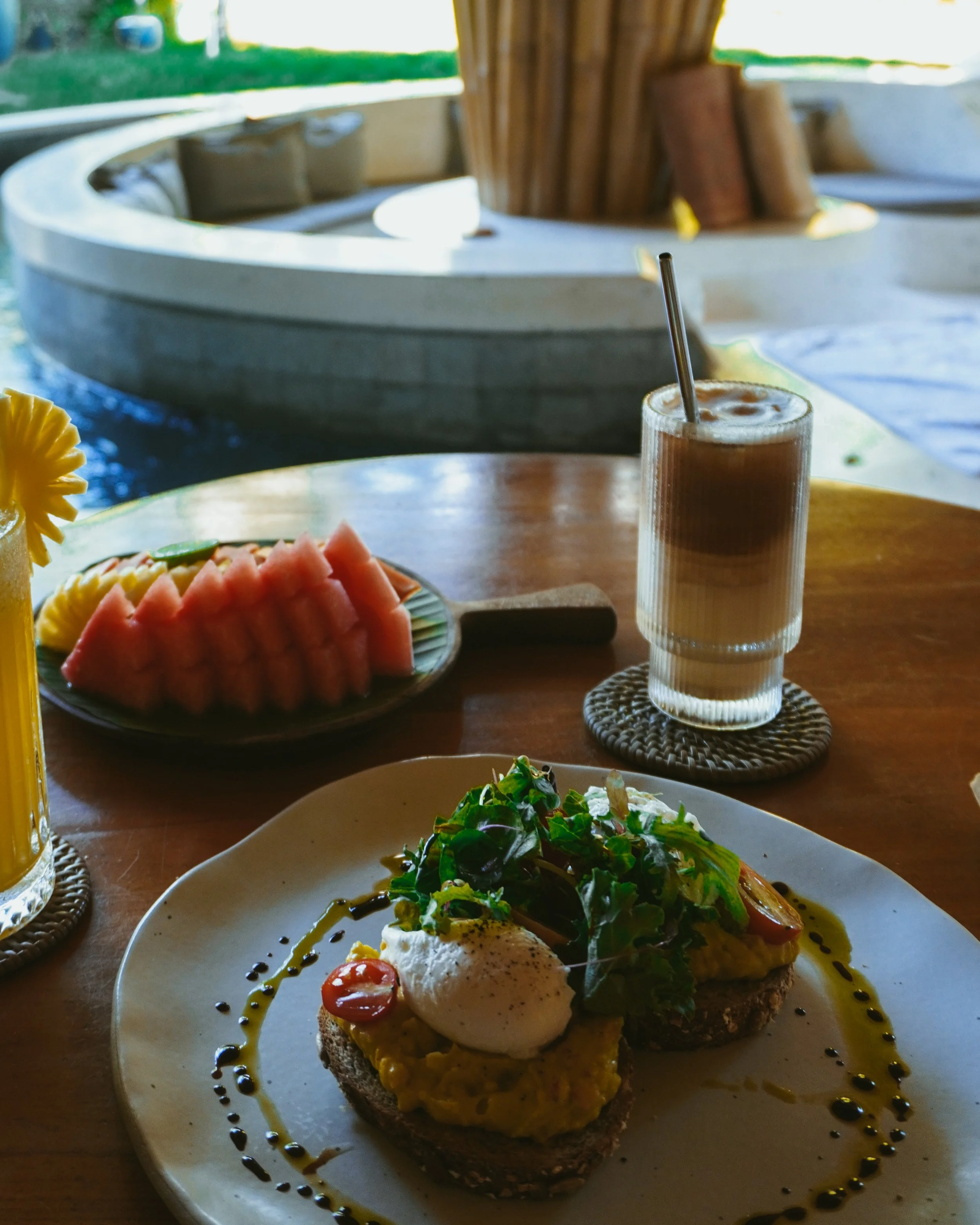 Fresh tropical breakfast is served beside a peaceful bamboo lounge and water feature